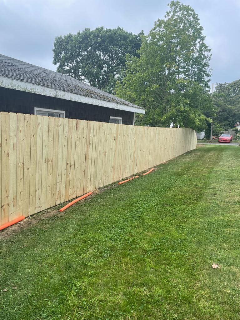 a wooden fence is sitting on top of a lush green lawn next to a house .