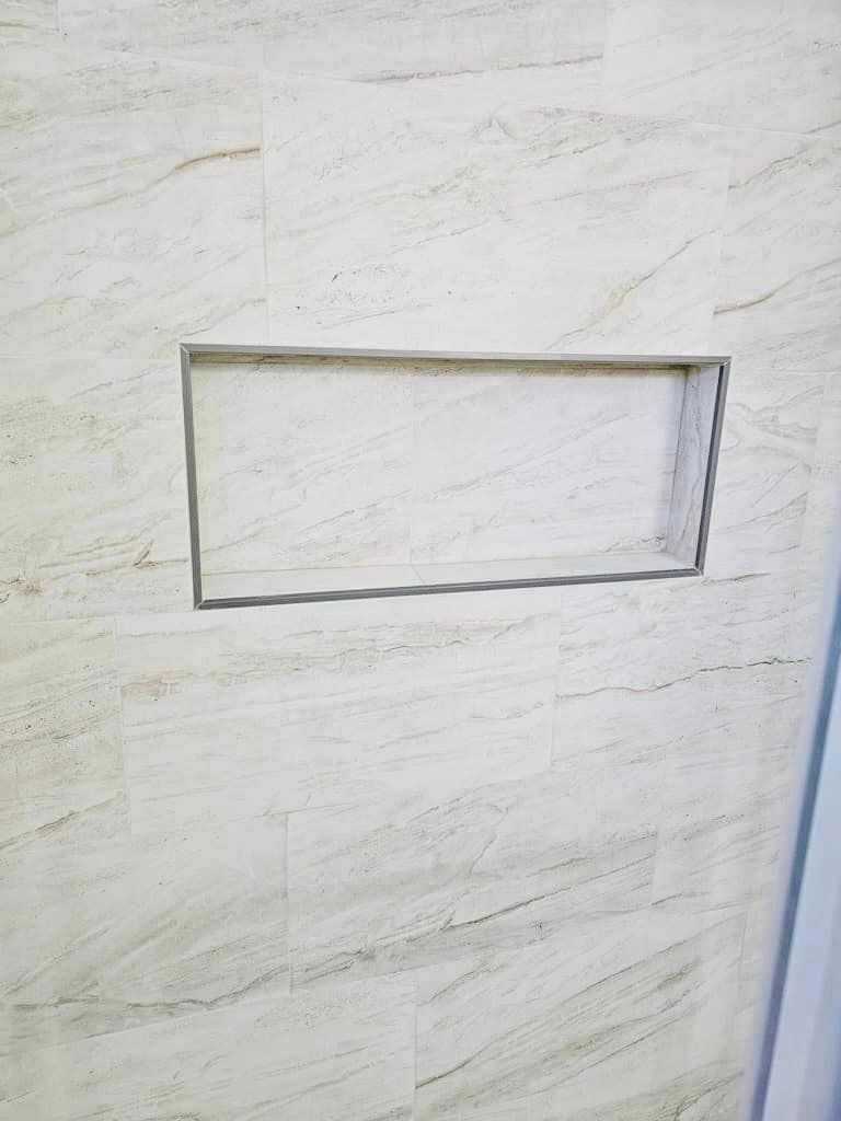 a white tile wall with a shelf in it .
