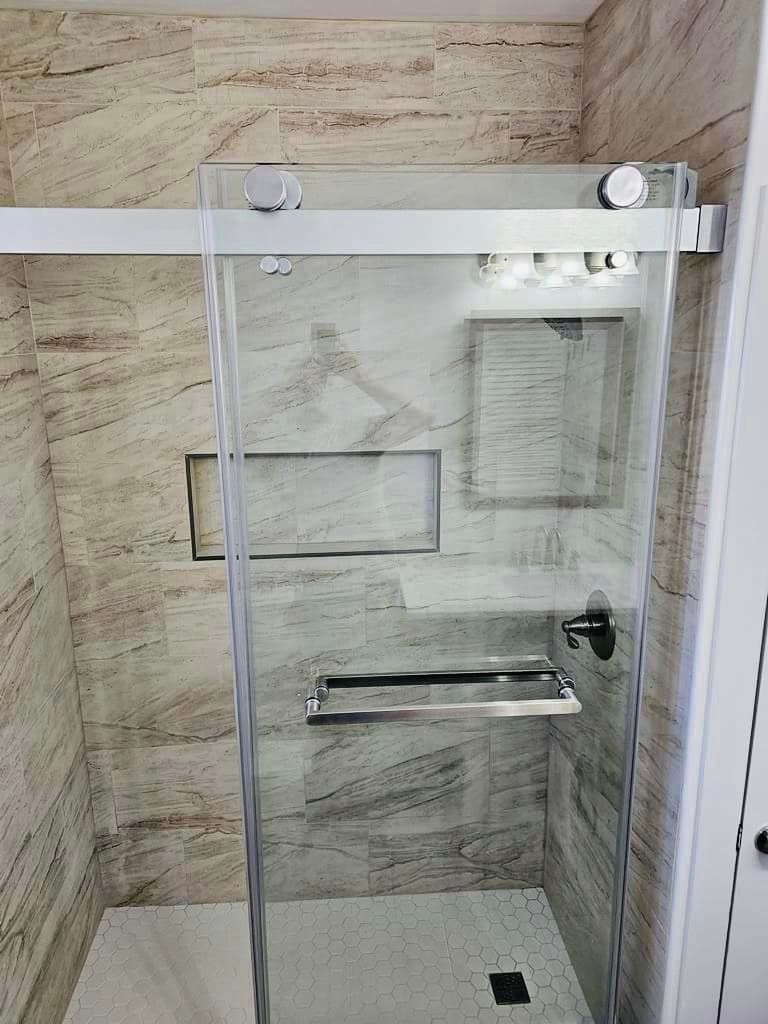 a bathroom with a sliding glass shower door and a marble wall .