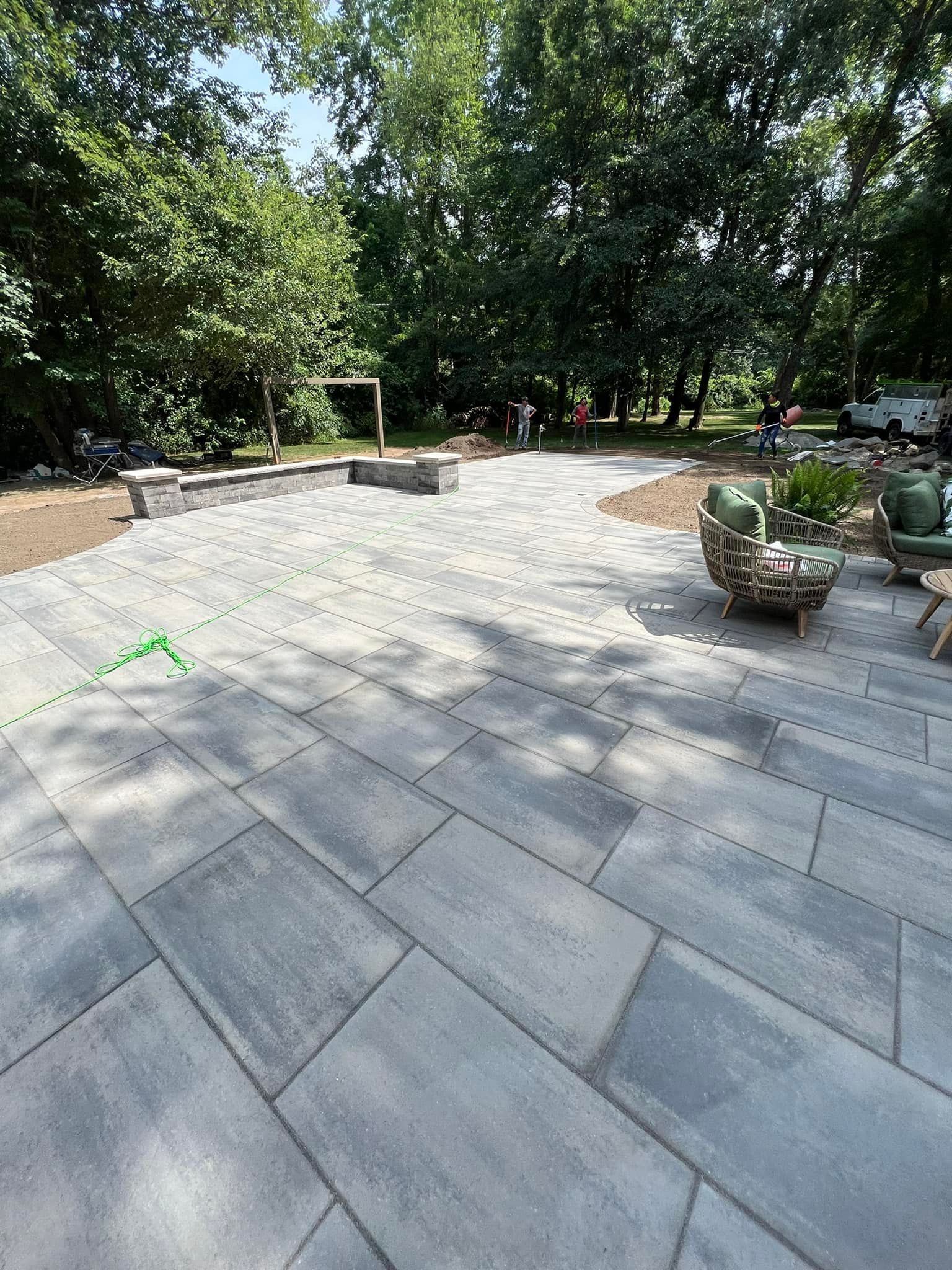 a large patio with chairs and a fire pit surrounded by trees .