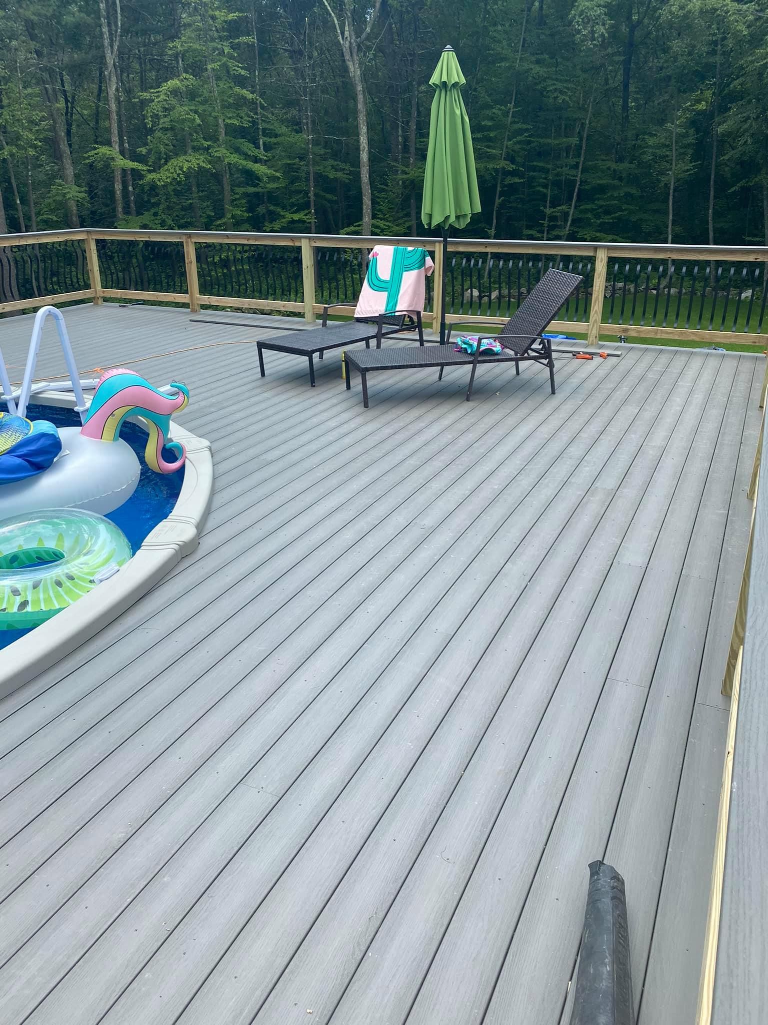 a deck with a pool , chairs , umbrellas and a fountain .