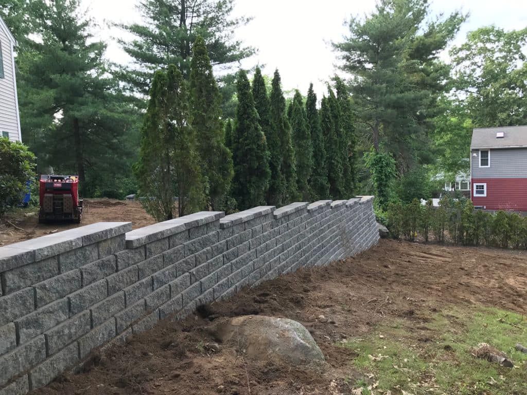 a brick wall is being built in the backyard of a house .