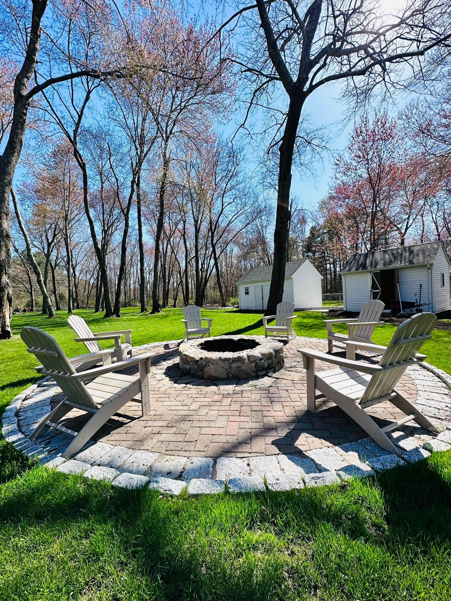 there is a fire pit in the middle of the yard with chairs around it .