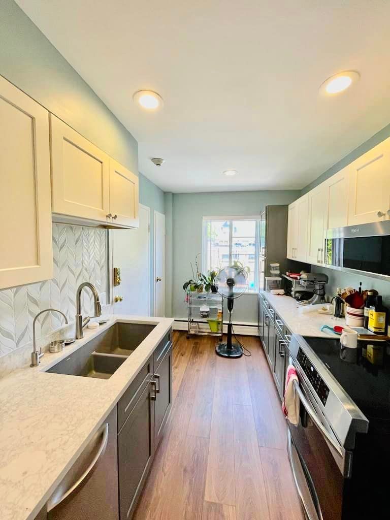 a long kitchen with stainless steel appliances , a sink , and a stove .