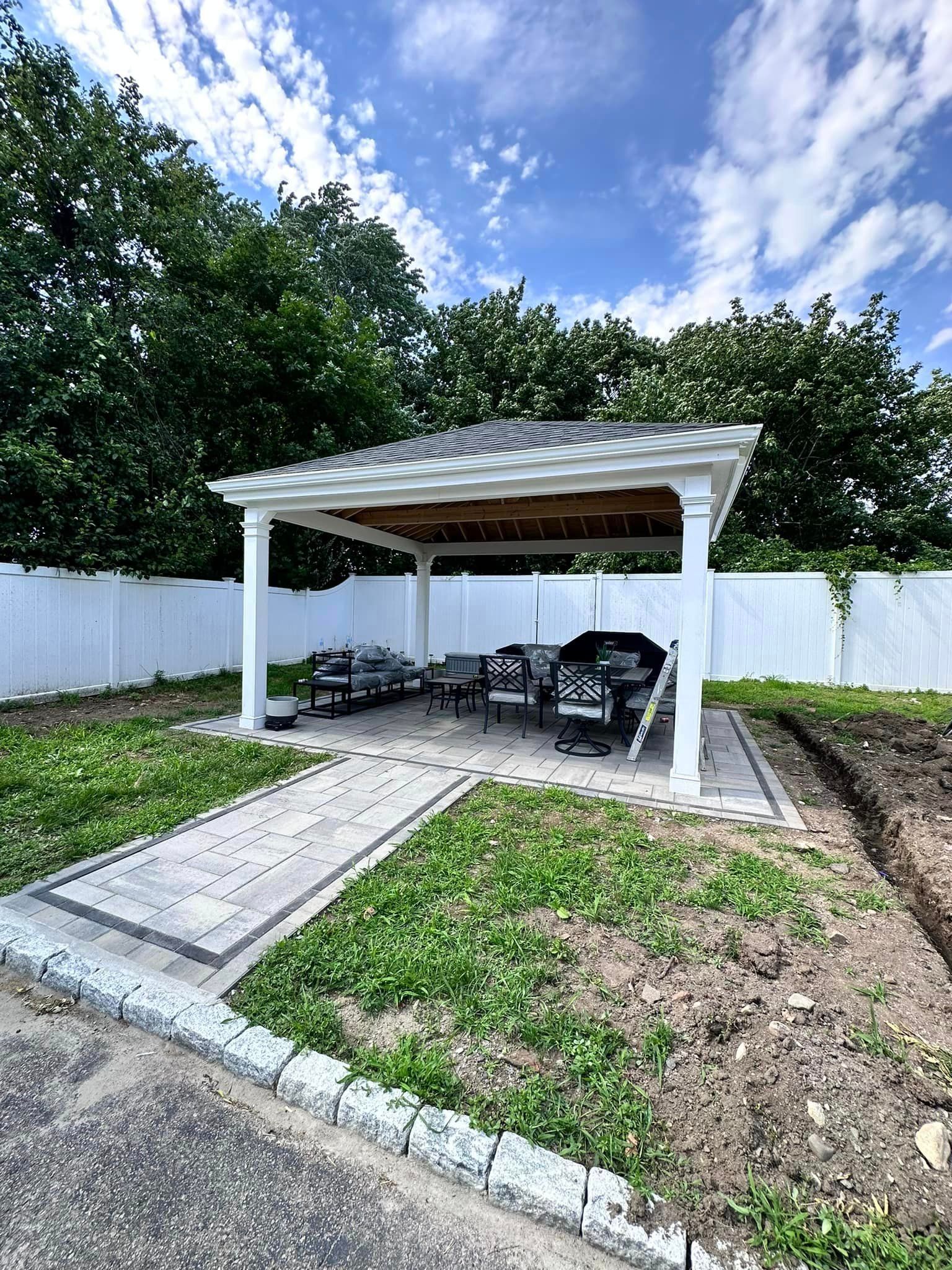 a white gazebo with a boat underneath it in a backyard .