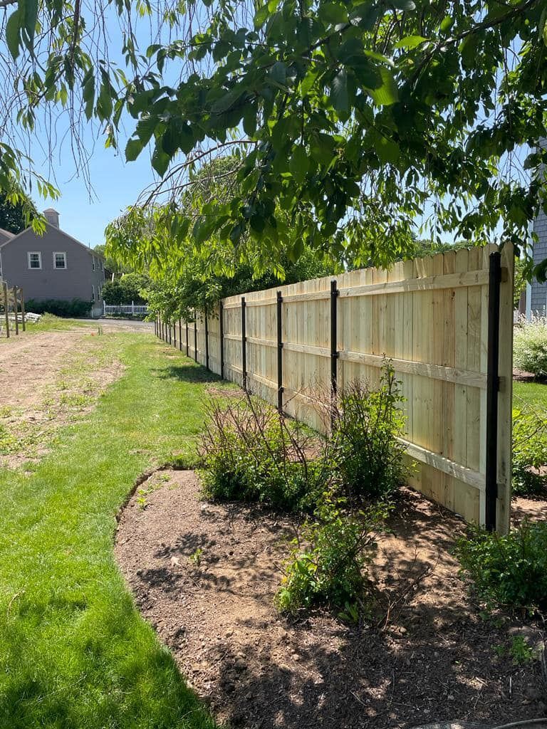 a wooden fence is surrounded by trees and bushes in a yard .