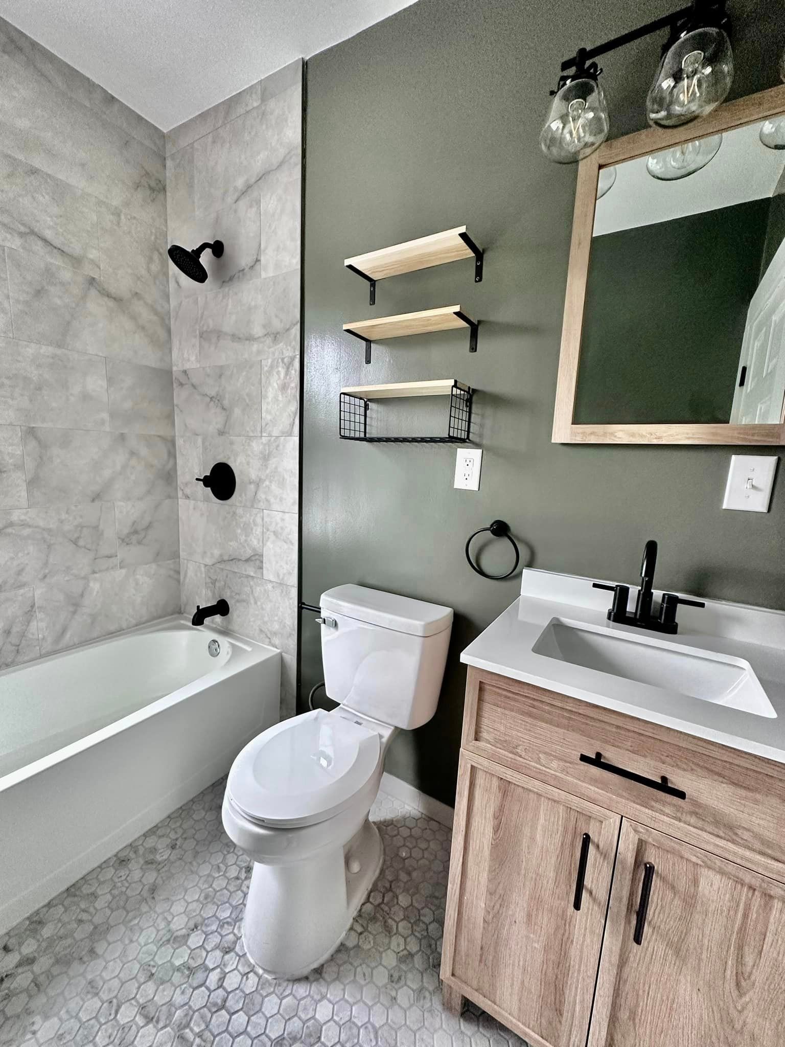 a bathroom with a toilet , sink , bathtub and mirror .