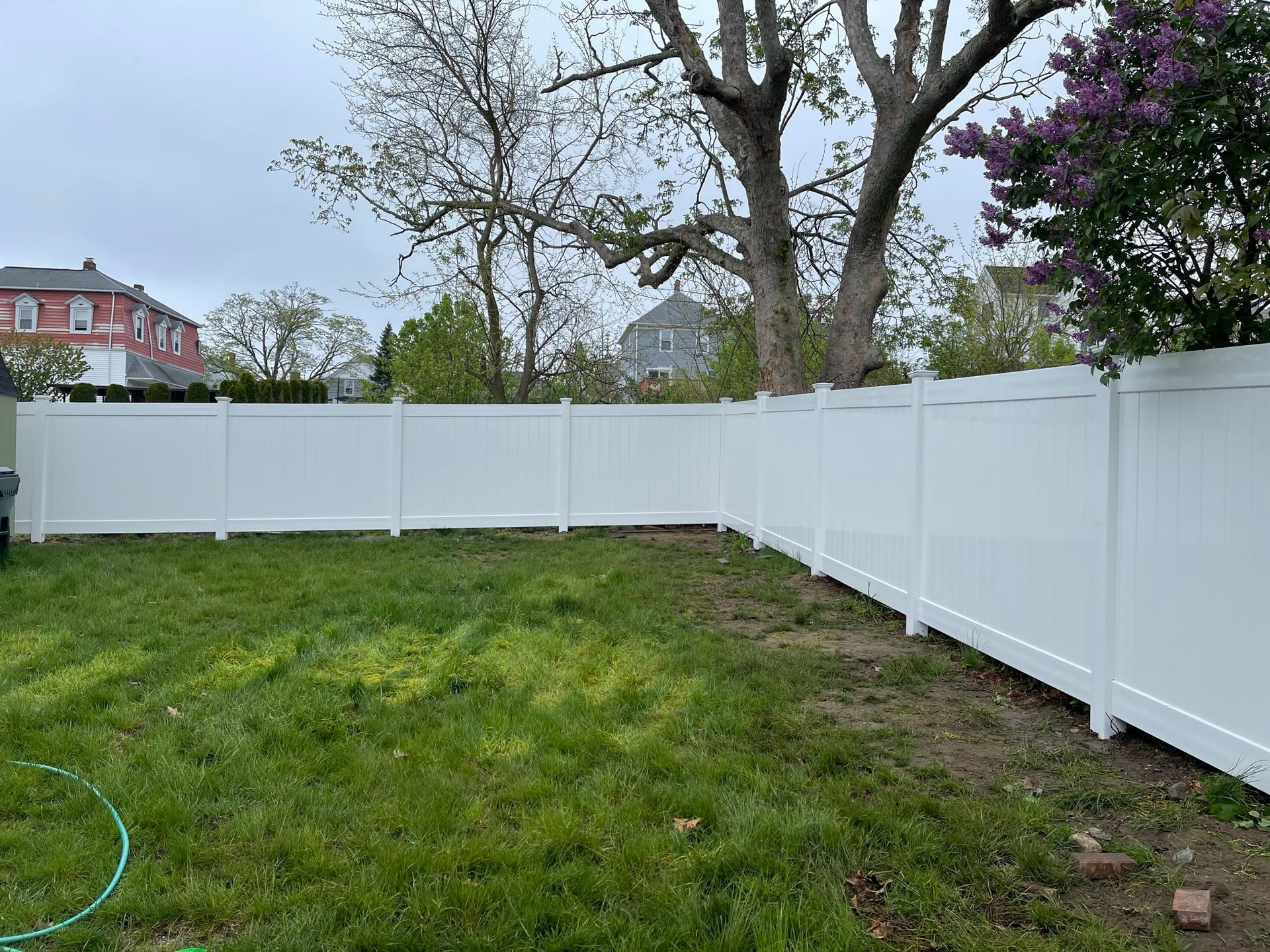 A white fence surrounds a lush green yard.