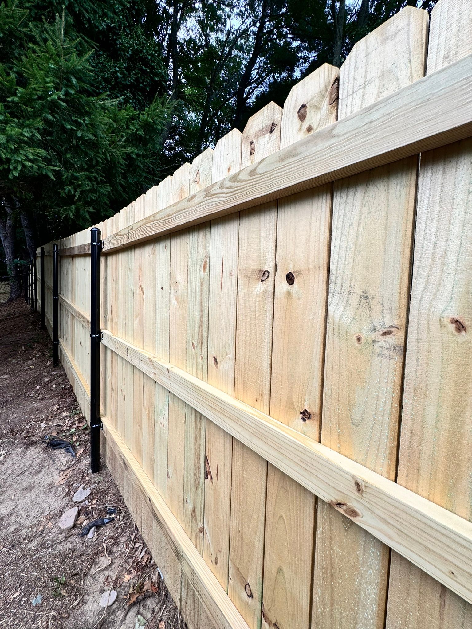 A wooden fence is sitting next to a dirt path.