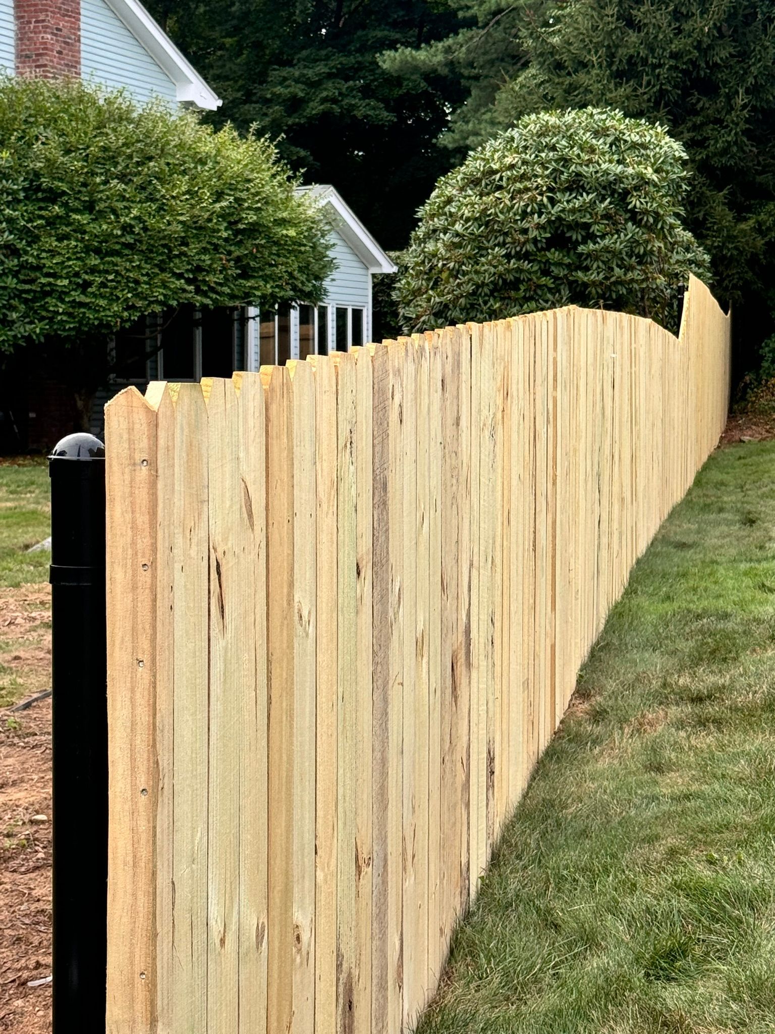 A wooden fence is sitting in the grass next to a house.