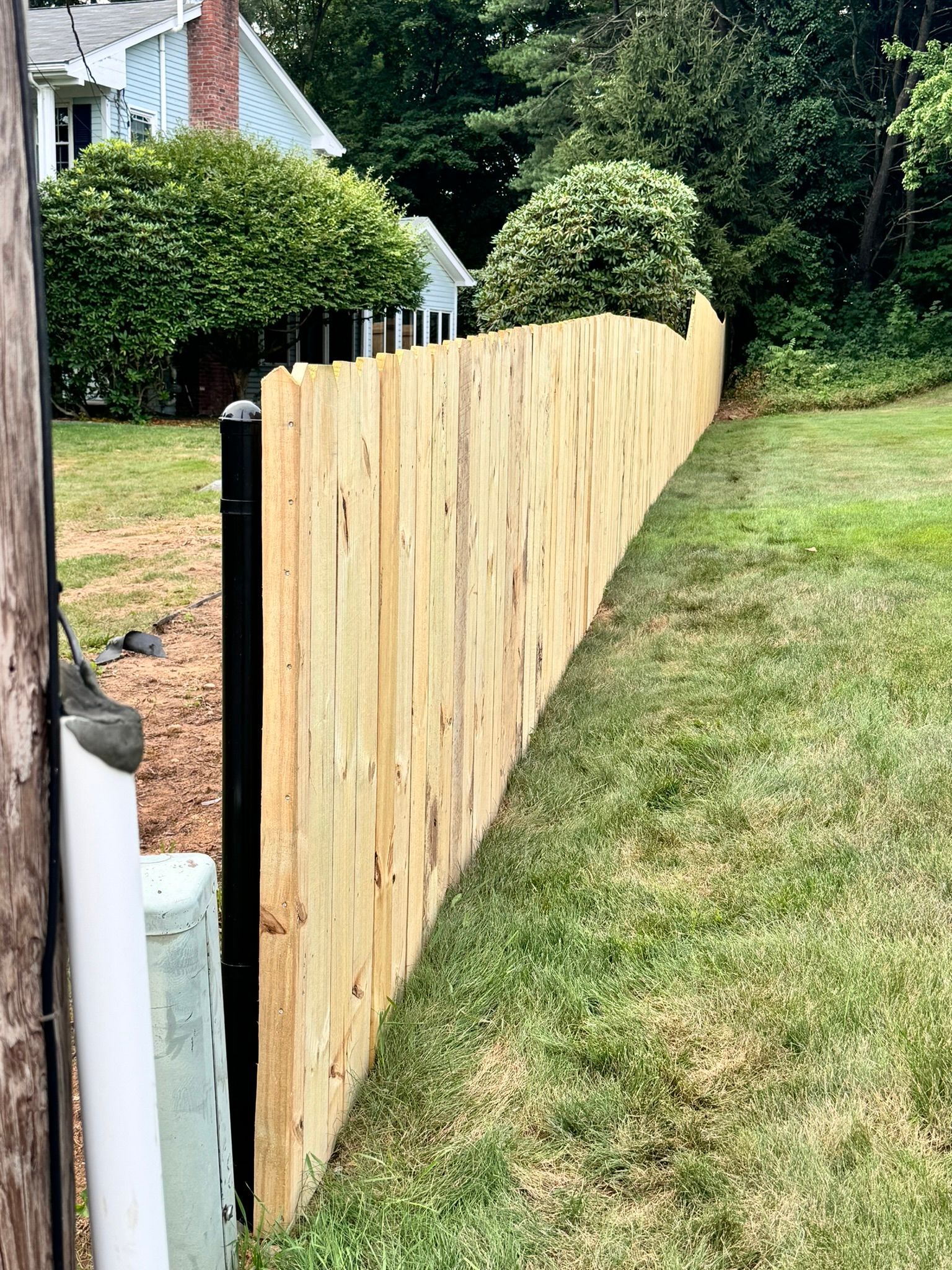 A wooden fence is sitting in the middle of a lush green yard.