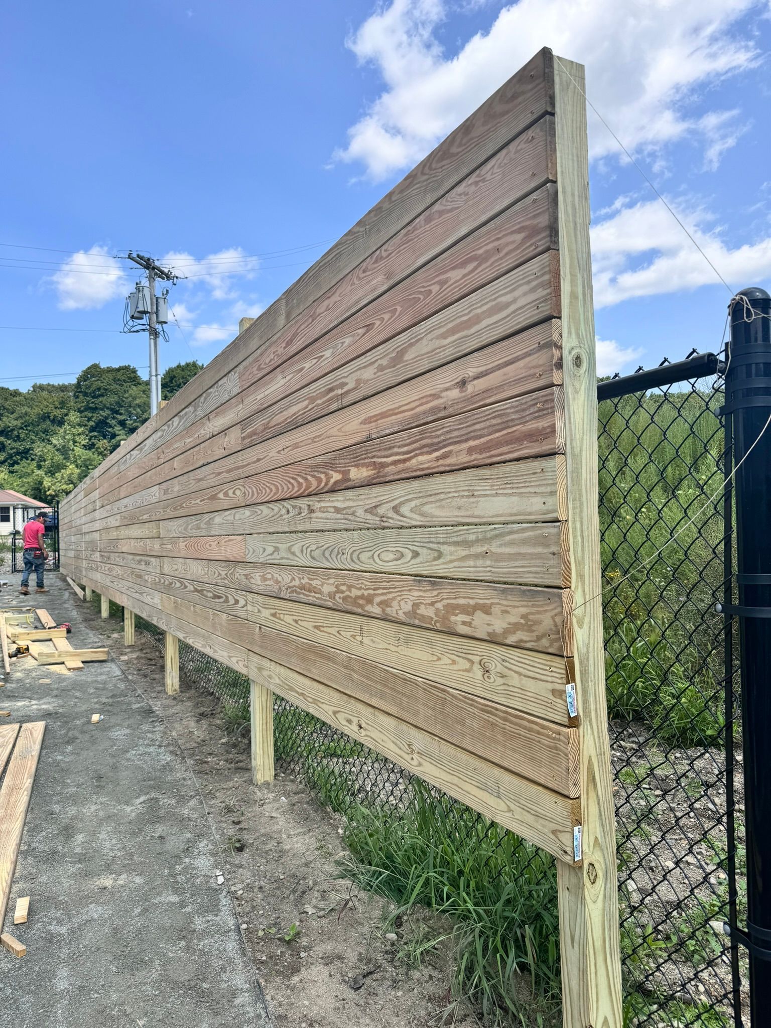 A wooden fence is being built next to a chain link fence.