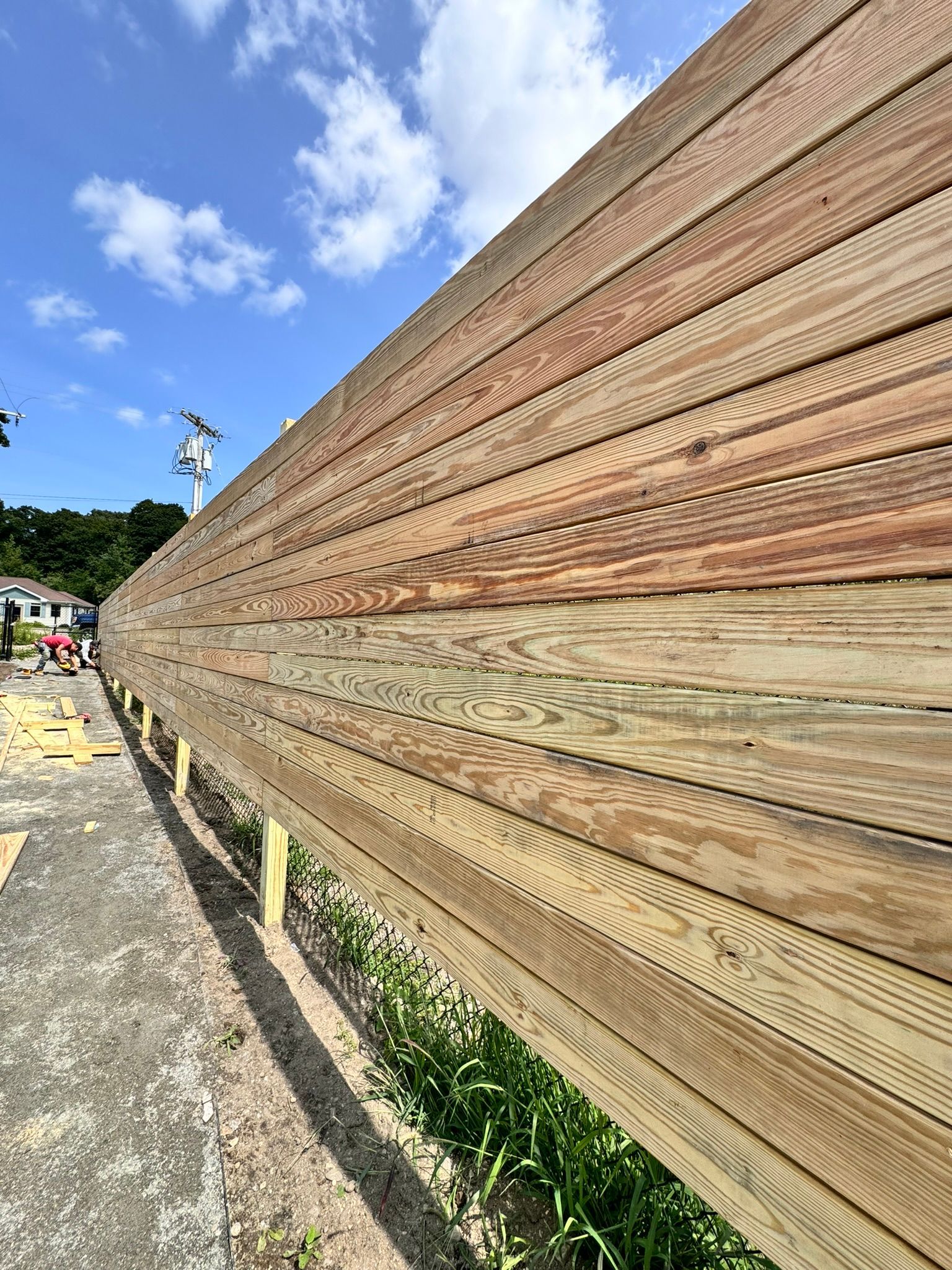 A long wooden fence is being built next to a road