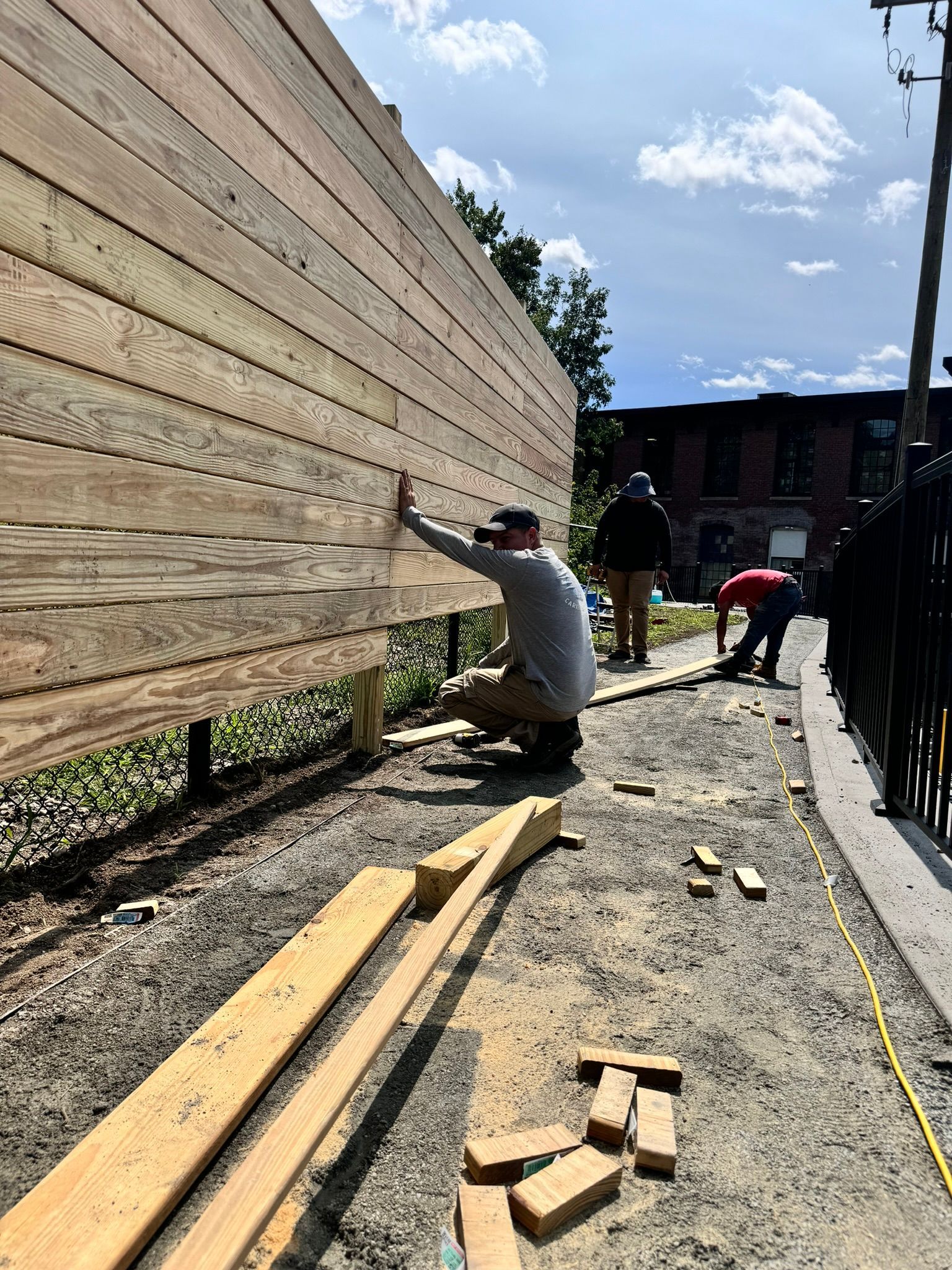 A group of people are working on a wooden fence.