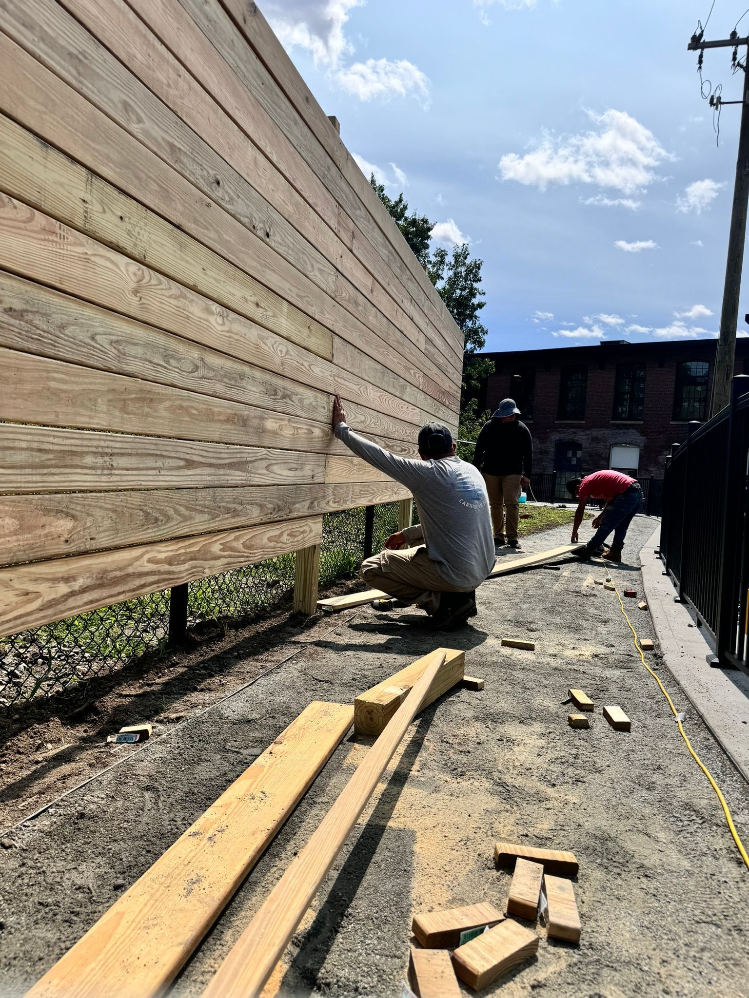 A group of people are working on a wooden fence.