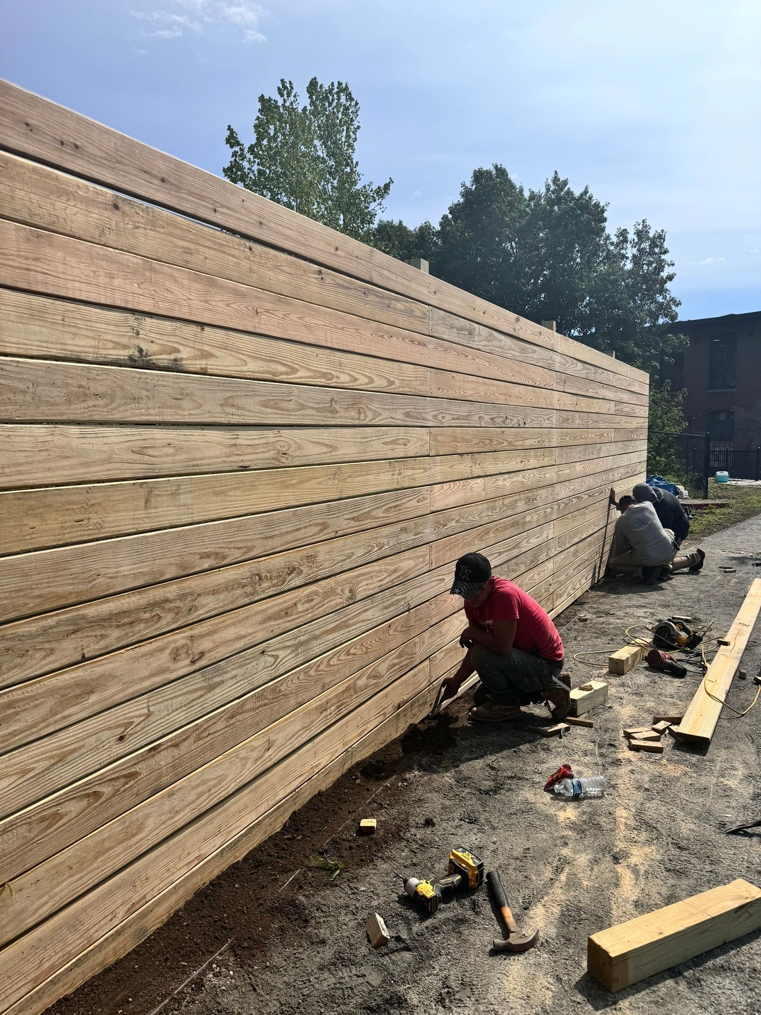 A group of people are working on a wooden fence