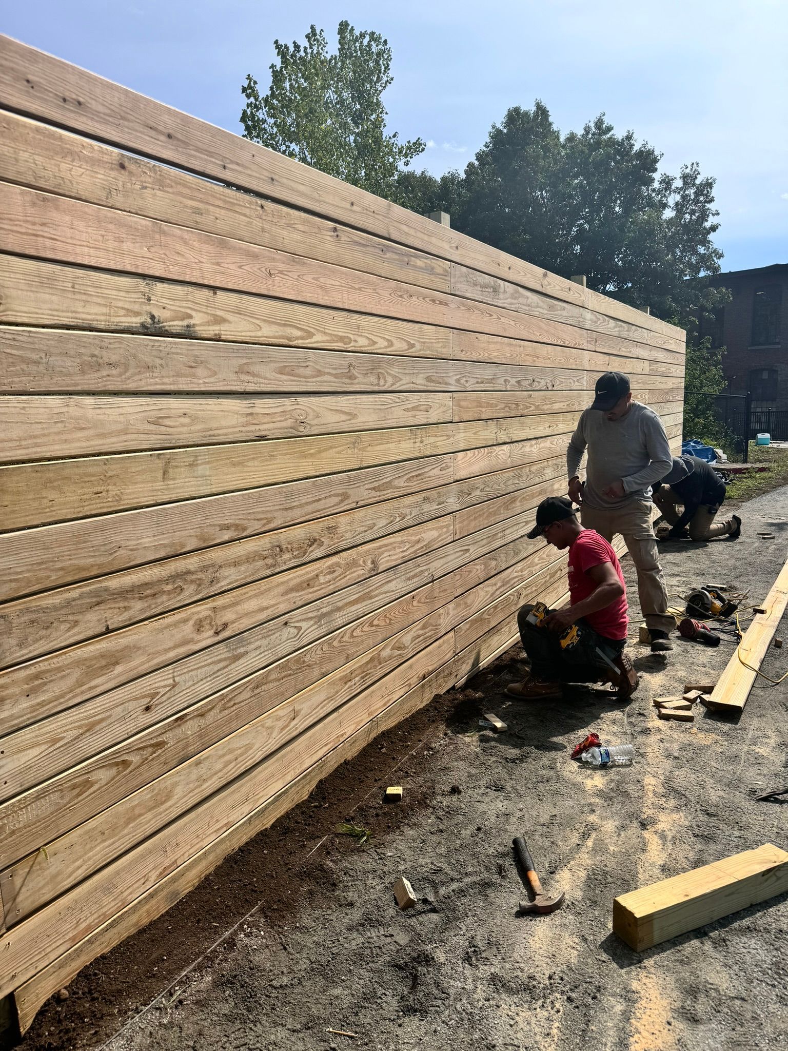 A group of men are working on a wooden fence.