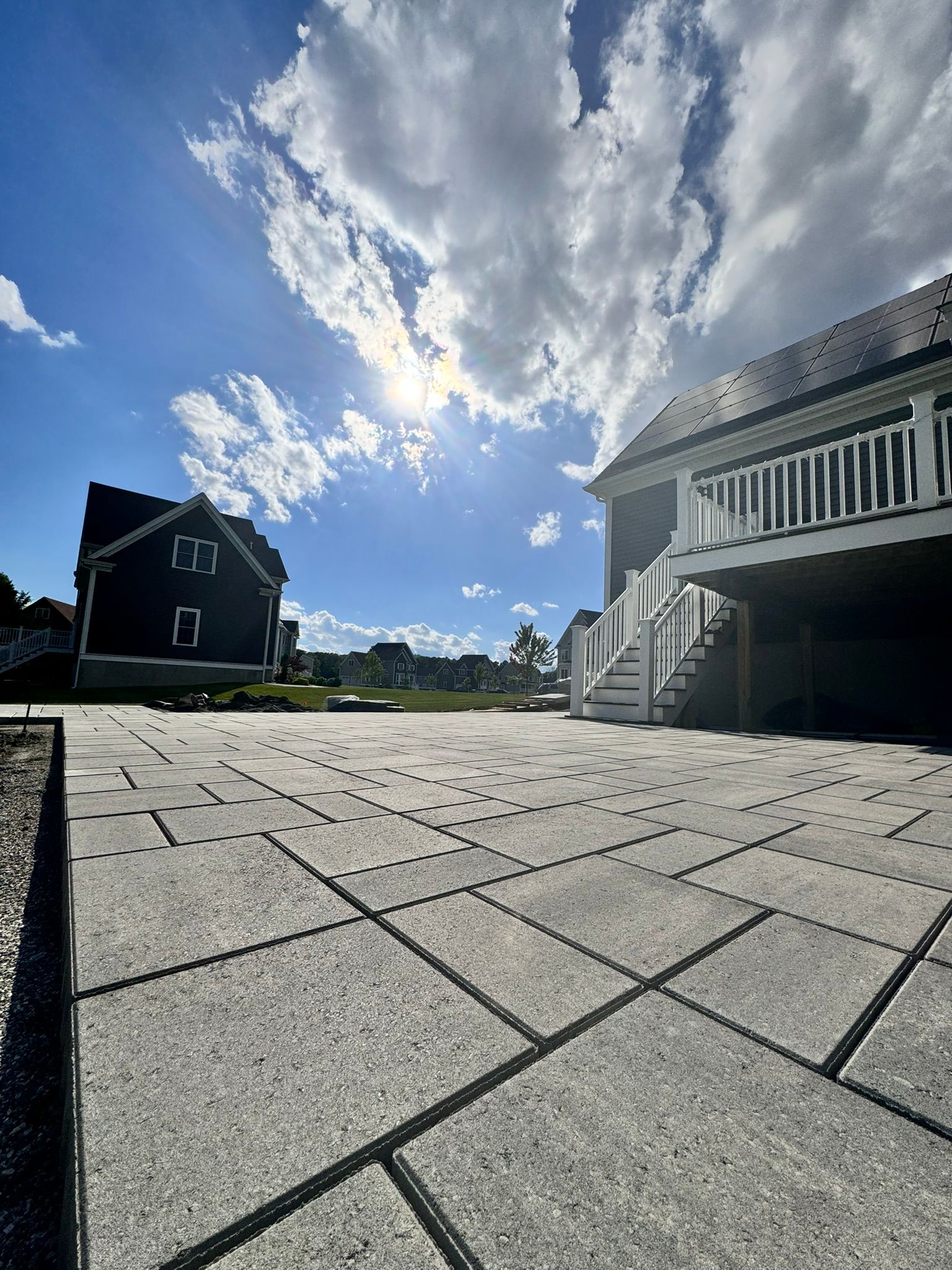 A large house with stairs leading up to it is sitting on top of a concrete driveway