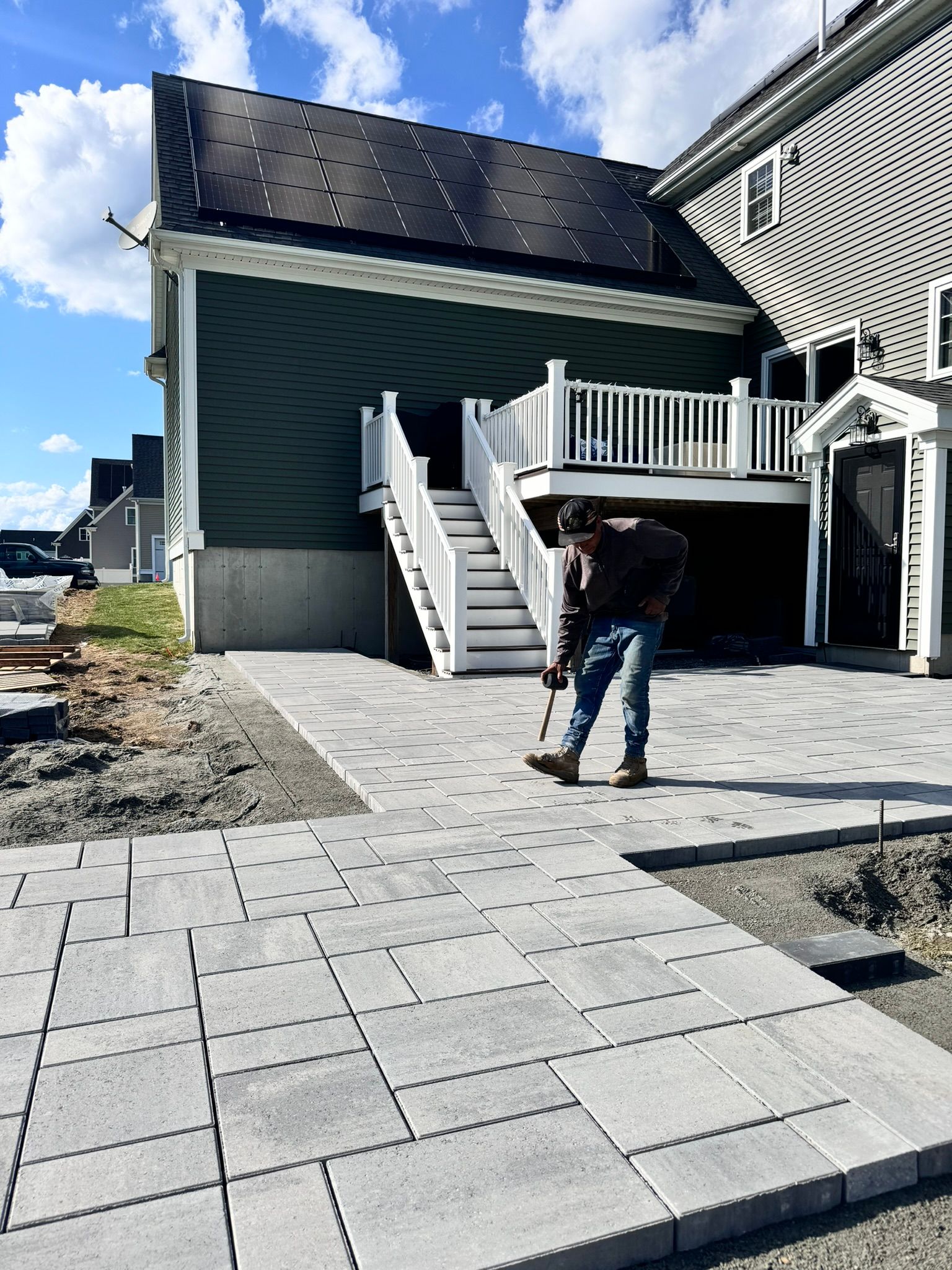 A man is working on a patio in front of a house