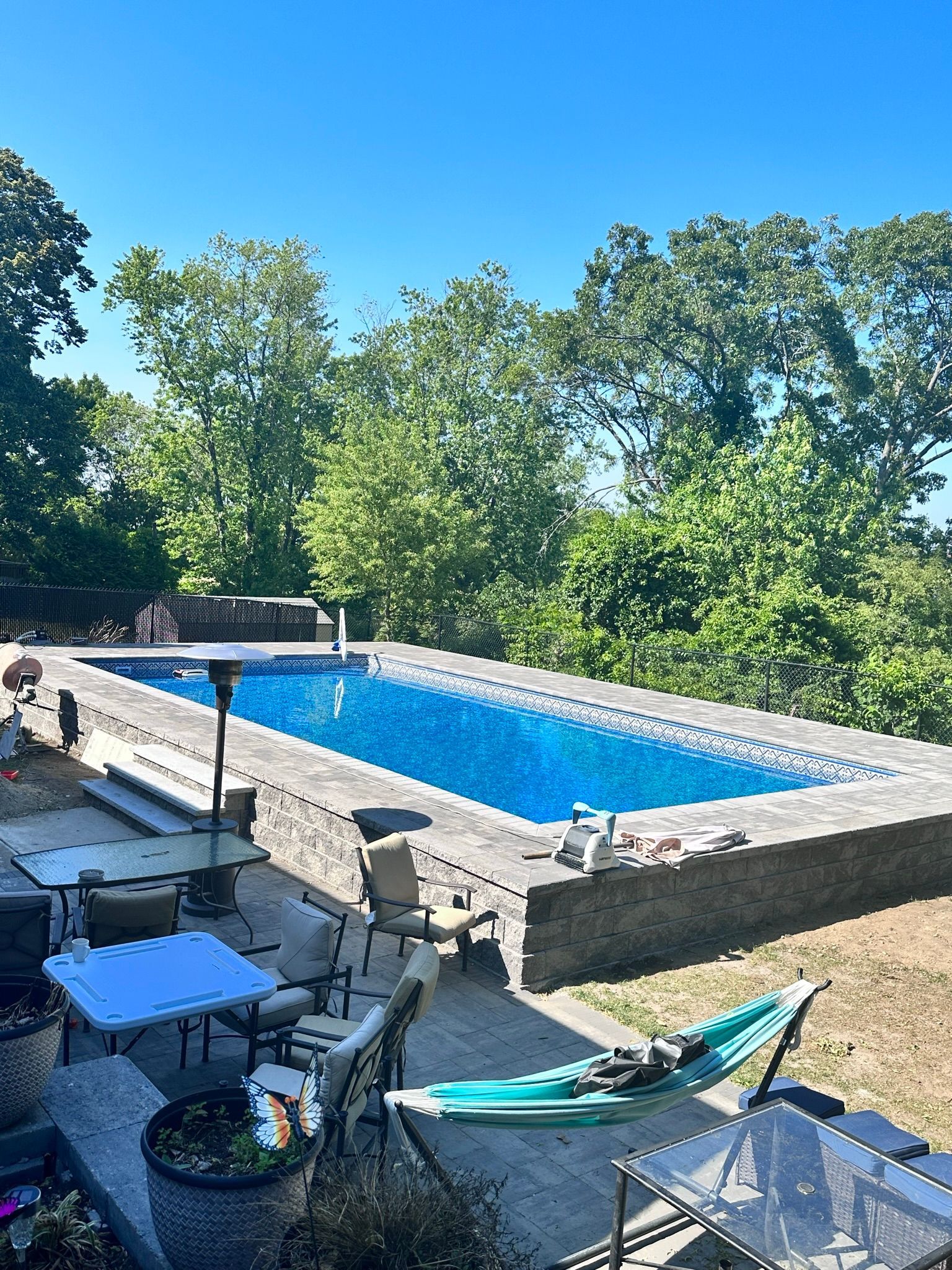 A large swimming pool is surrounded by a patio area with tables and chairs