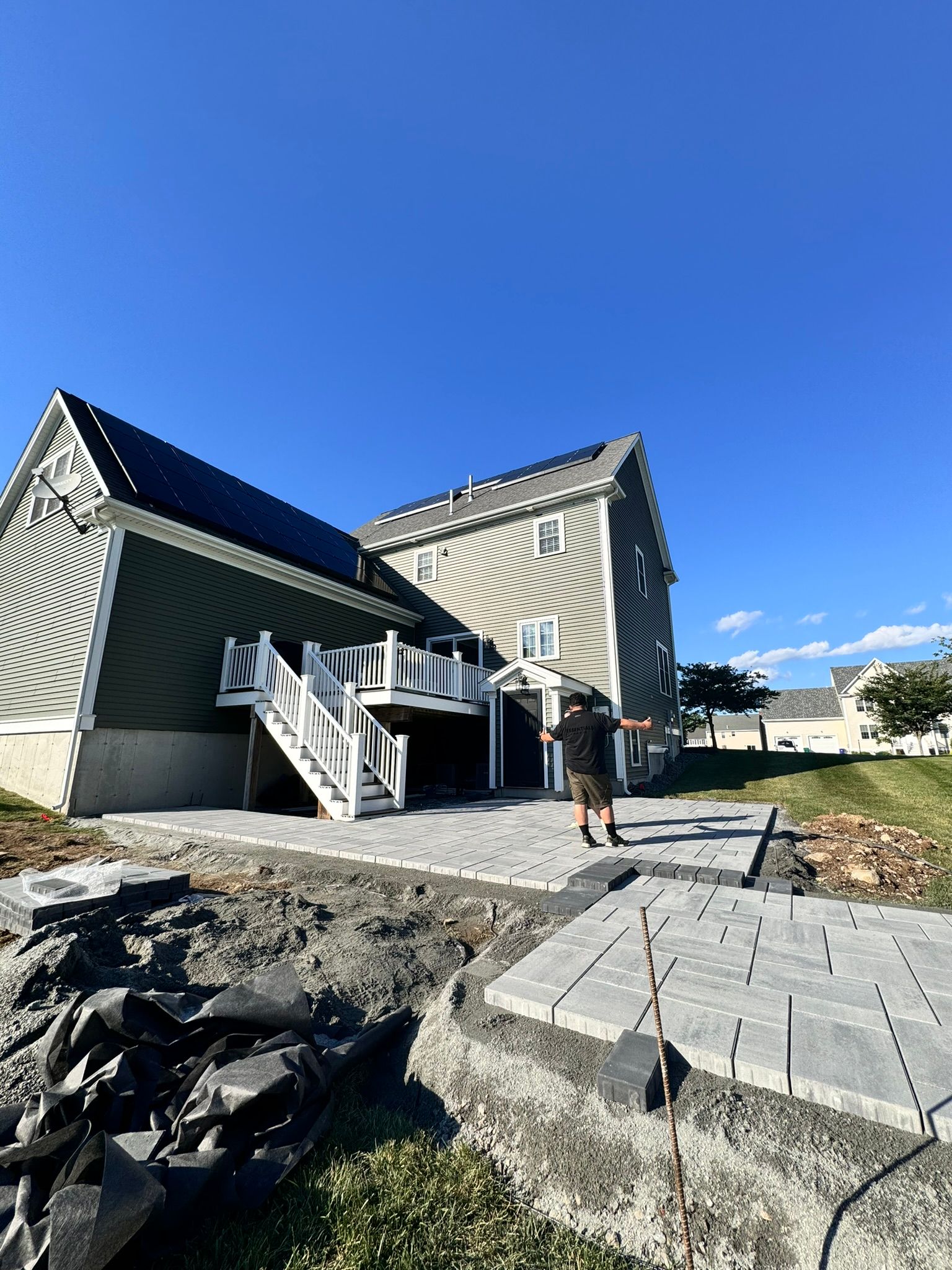 A man is standing in front of a large house with stairs