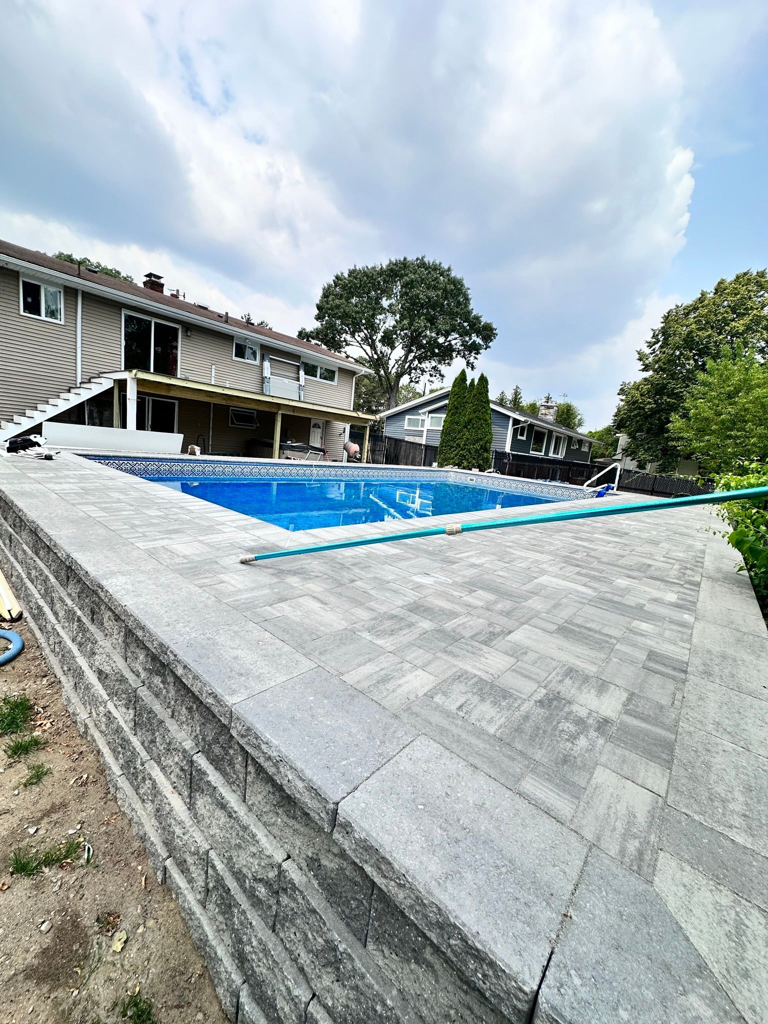 There is a large swimming pool in the backyard of a house