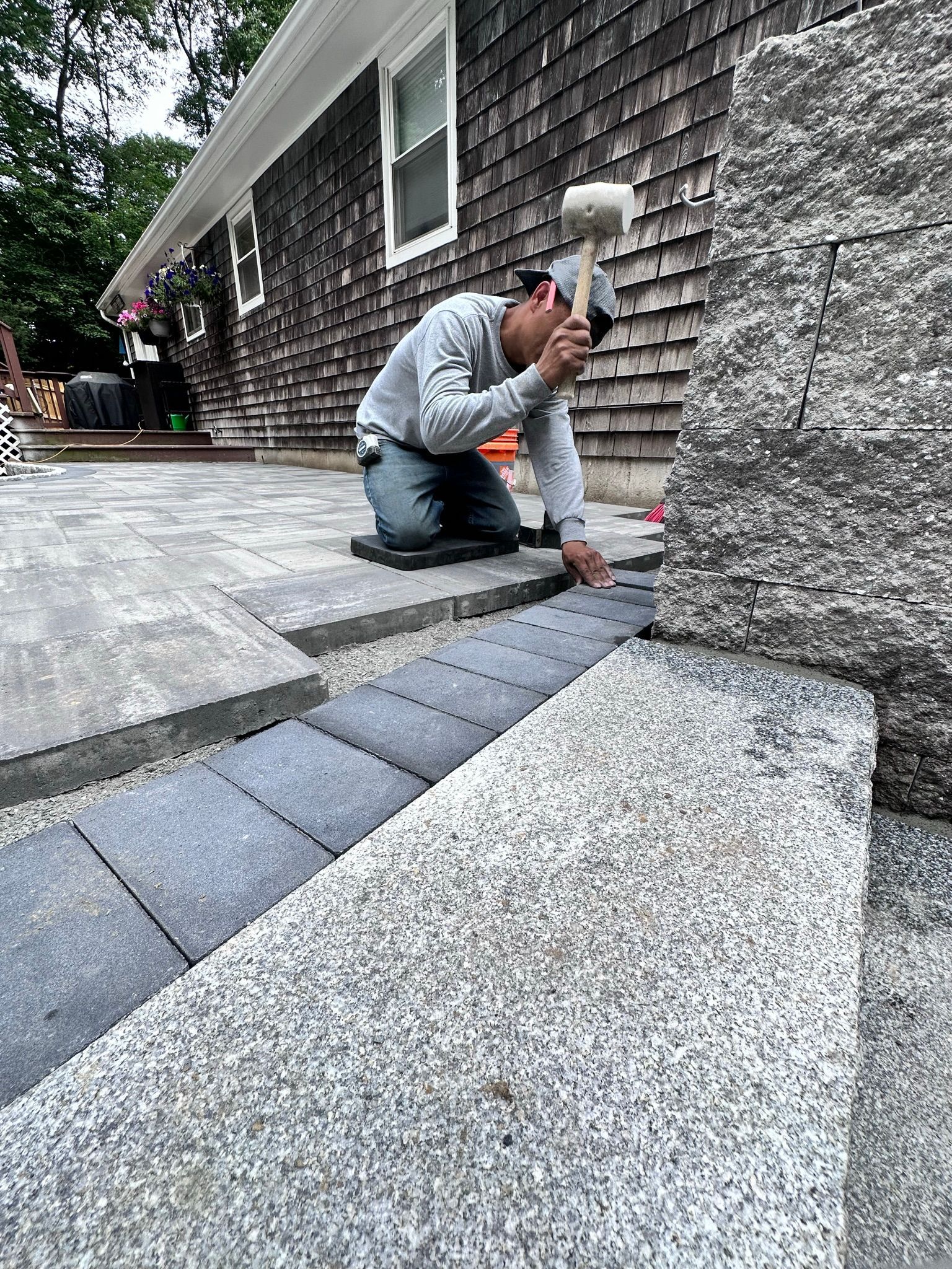 A man is kneeling down while holding a hammer