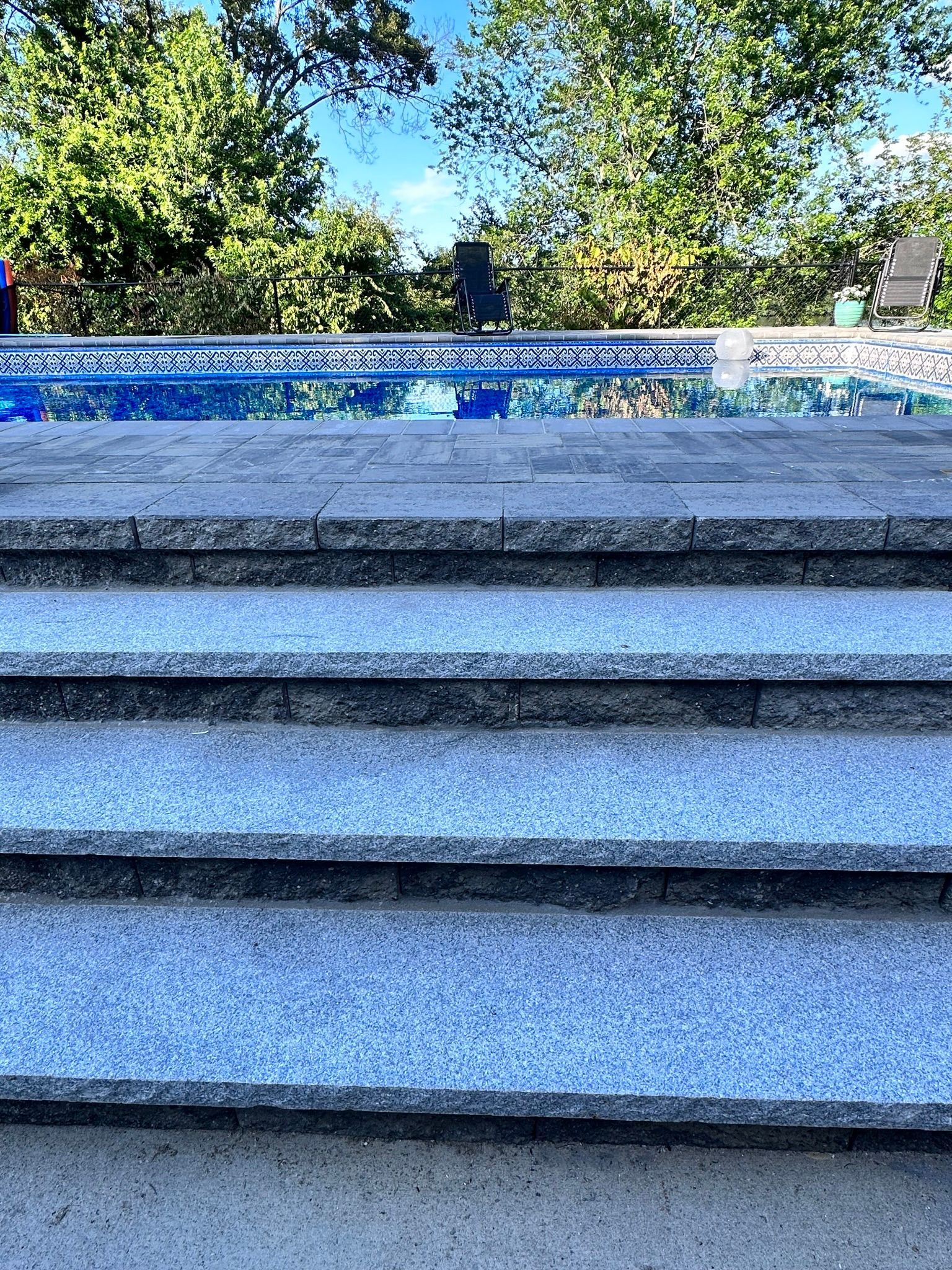 A set of stairs leading up to a pool with trees in the background