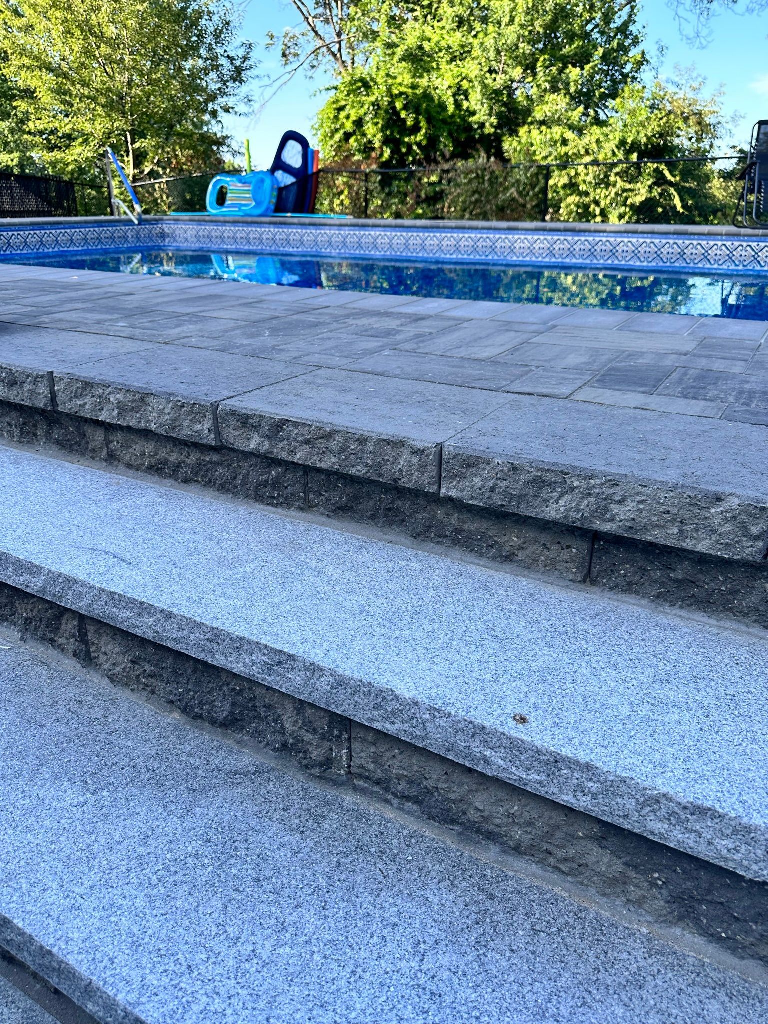 A staircase leading to a swimming pool with a blue chair in the background
