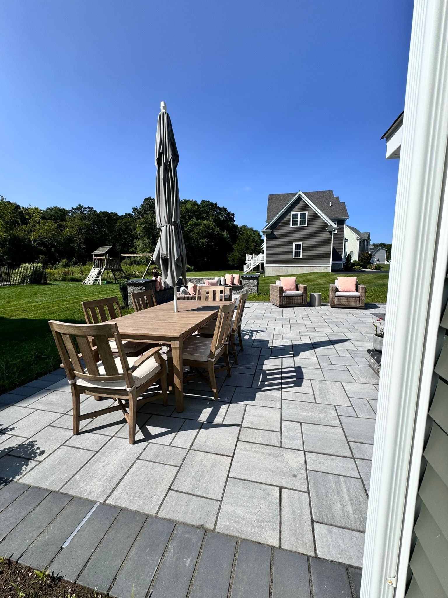 A patio with a table and chairs and umbrellas in front of a house