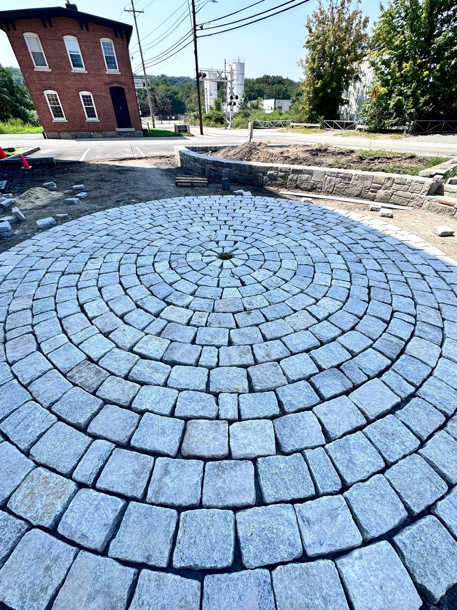 A circular stone walkway is being built in front of a brick building