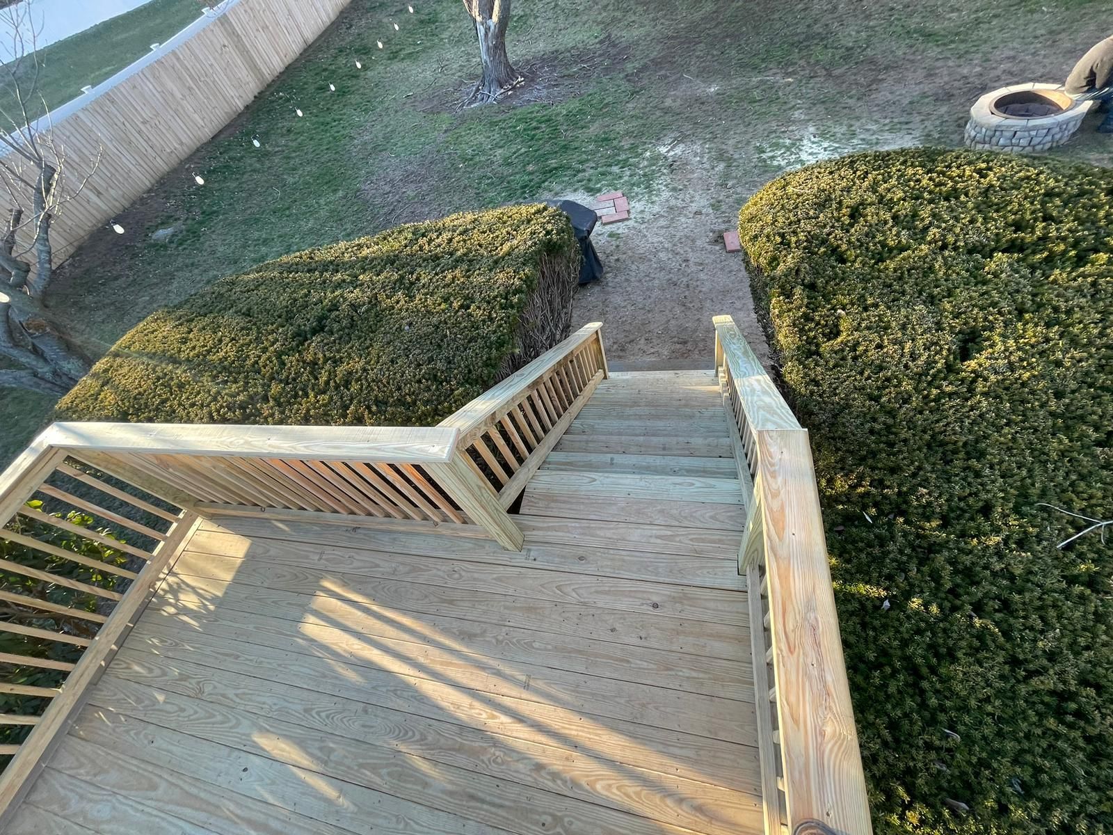 A wooden deck with stairs leading up to it and a fence in the background.