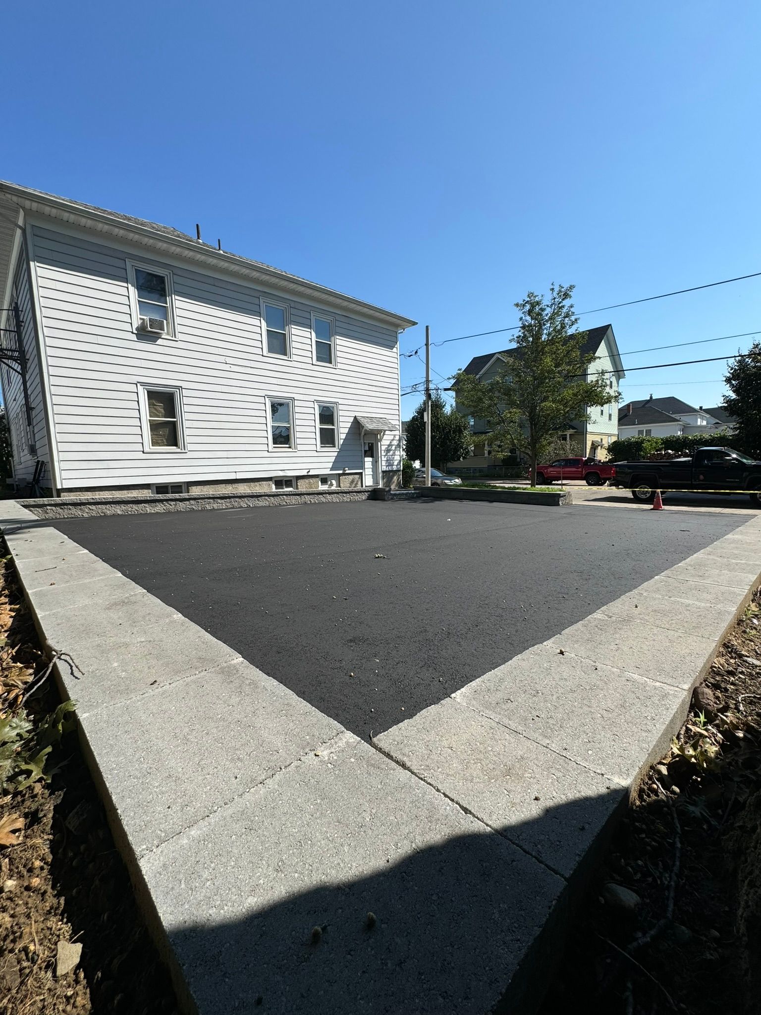 A white house with a black driveway in front of it.