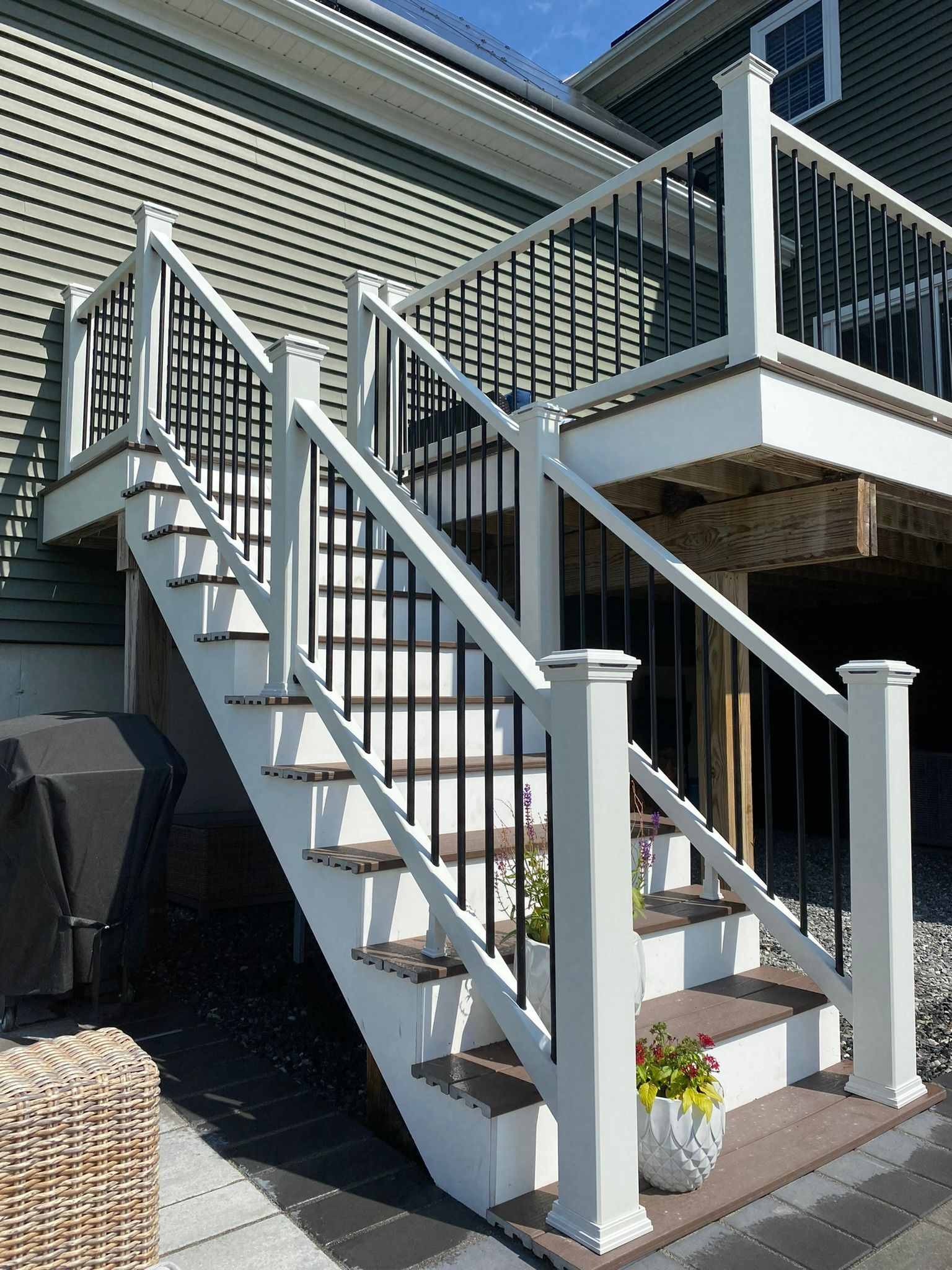 A white deck with stairs and a black railing.