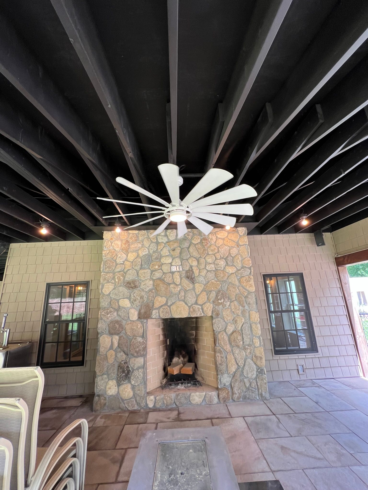 A ceiling fan is hanging from the ceiling above a stone fireplace.