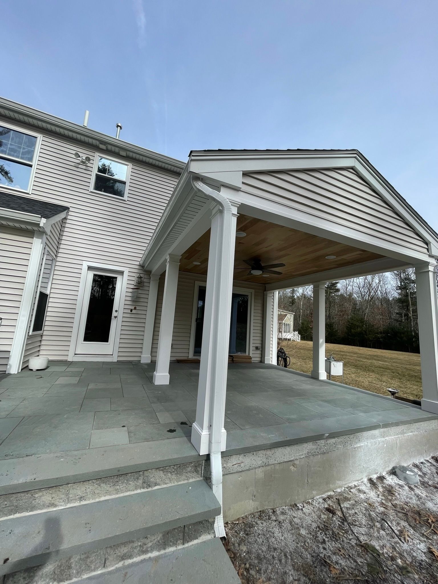 The back of a house with a covered patio and stairs.