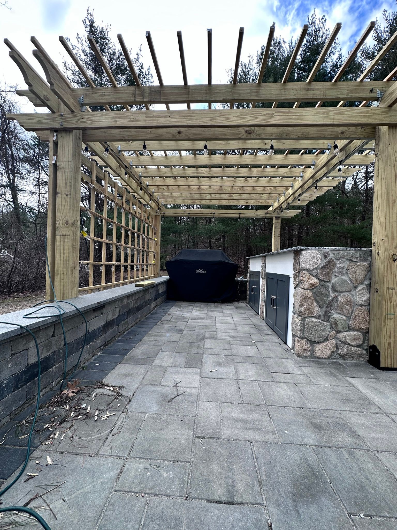 A wooden pergola is sitting on top of a stone patio.