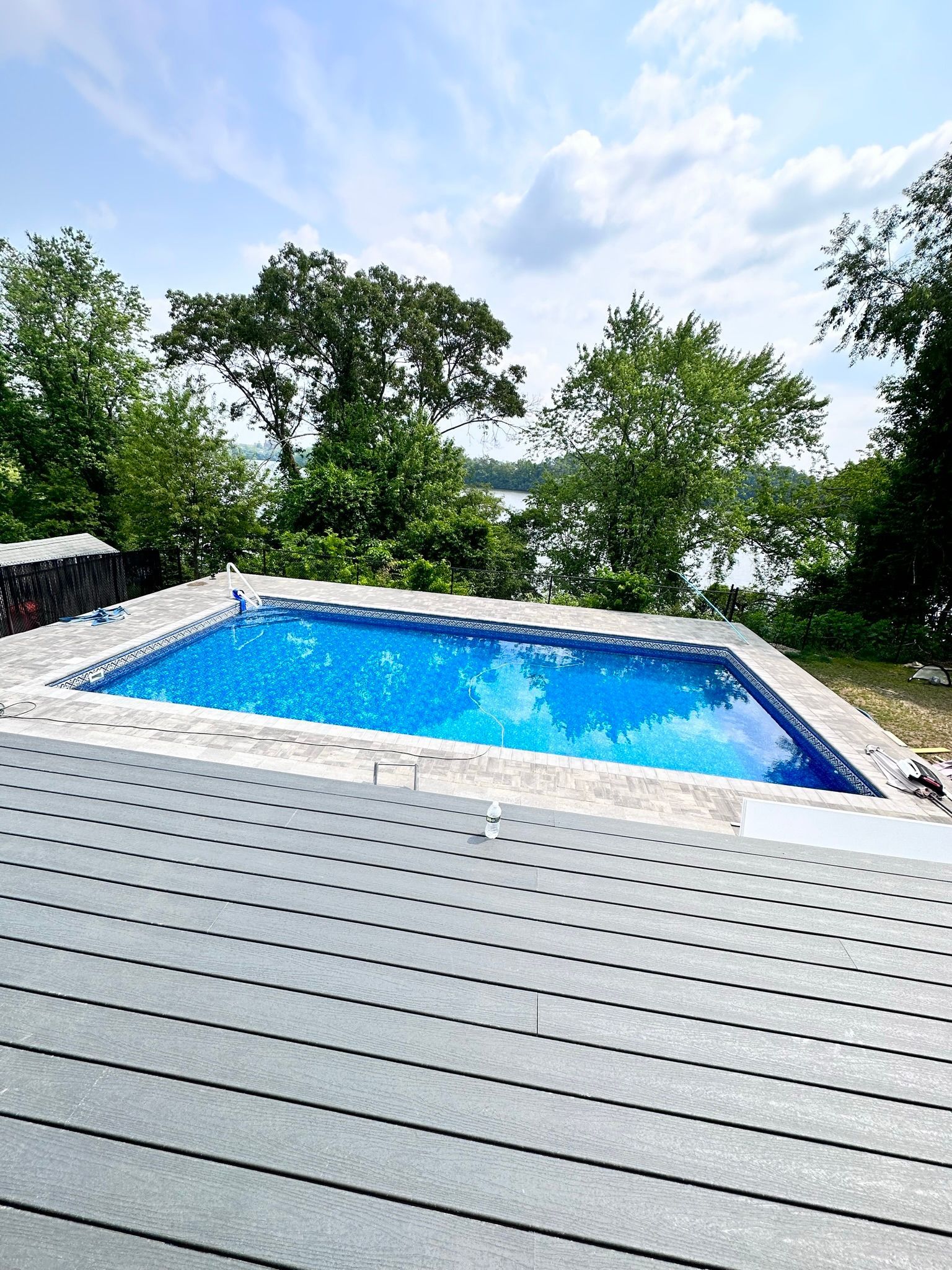 A large swimming pool is surrounded by trees and a deck.
