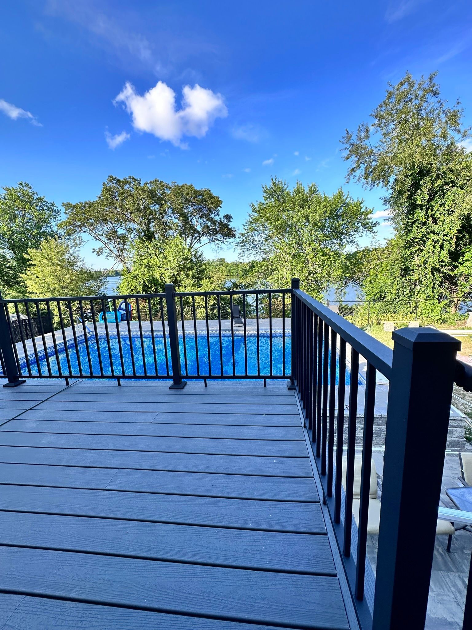 A view of a swimming pool from a deck with a fence.