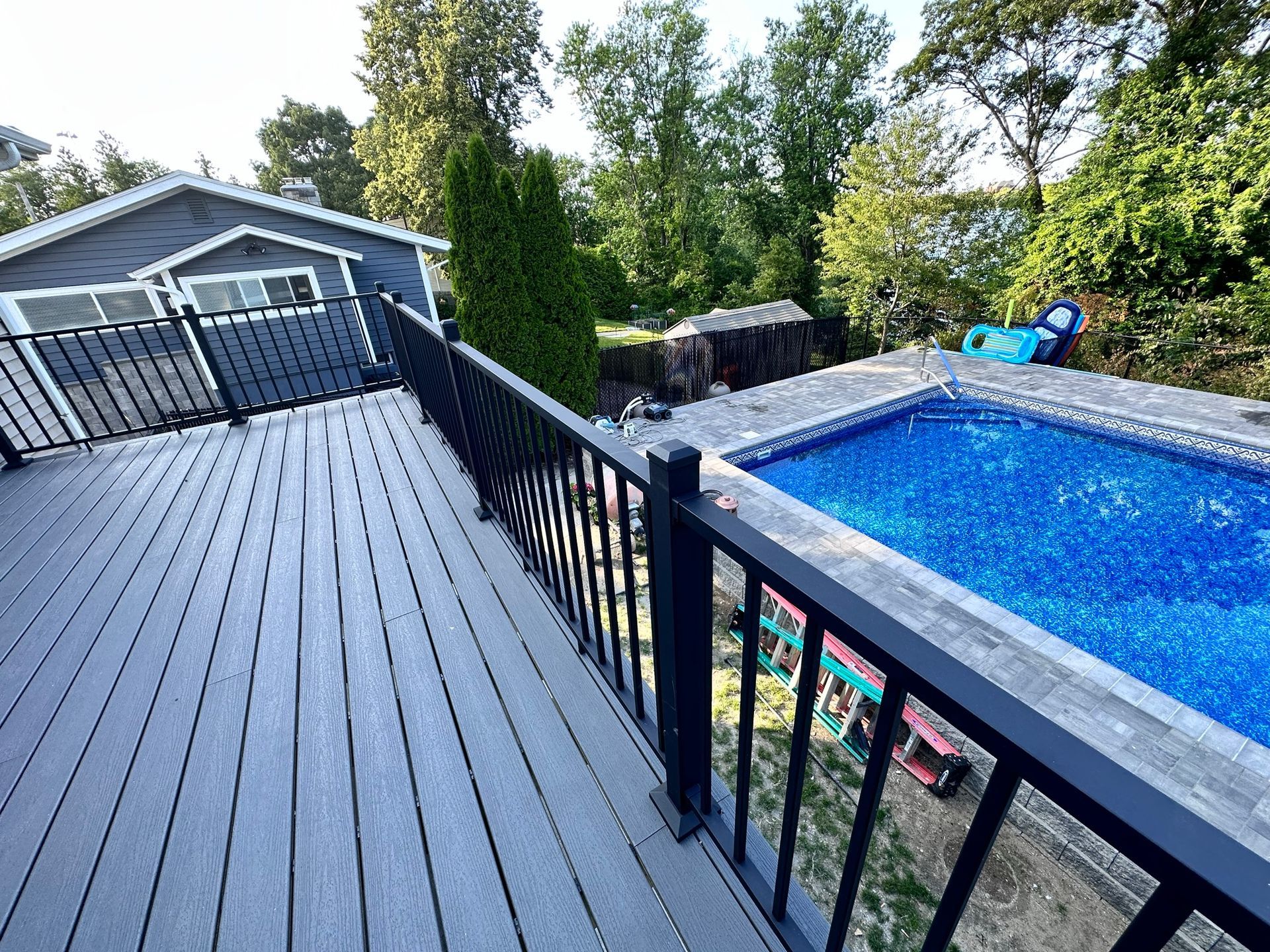 A large swimming pool is surrounded by a fence and a deck.