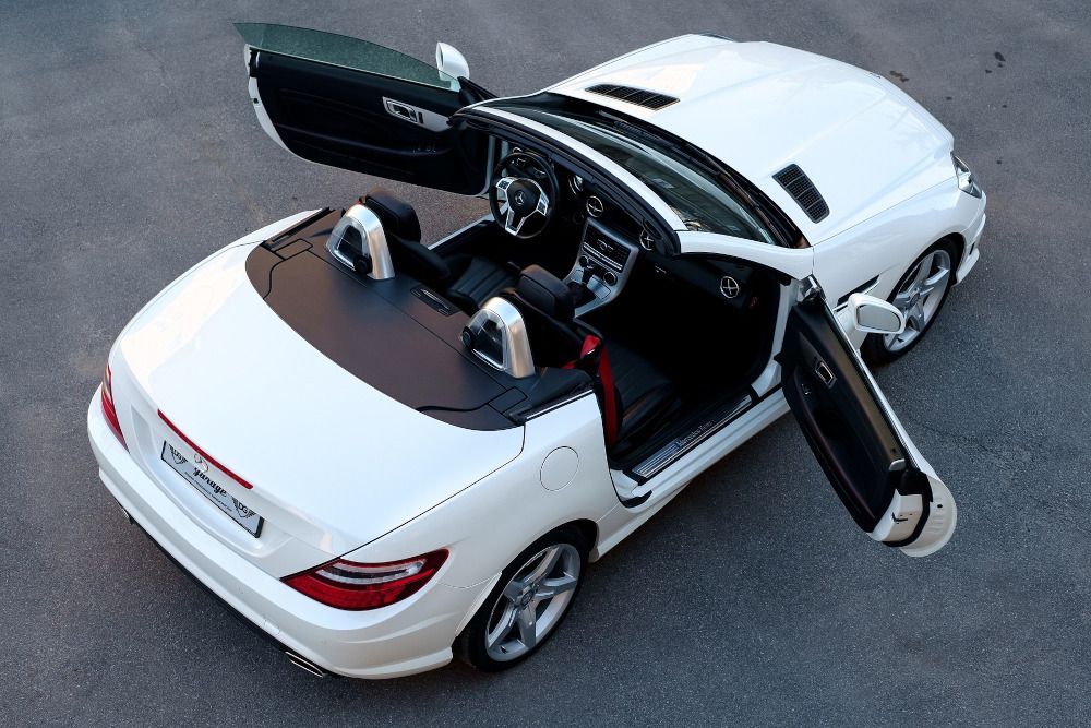 White convertible car with doors open on an asphalt road.
