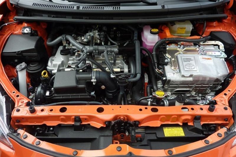 Orange car engine bay, showing gasoline engine and hybrid components.