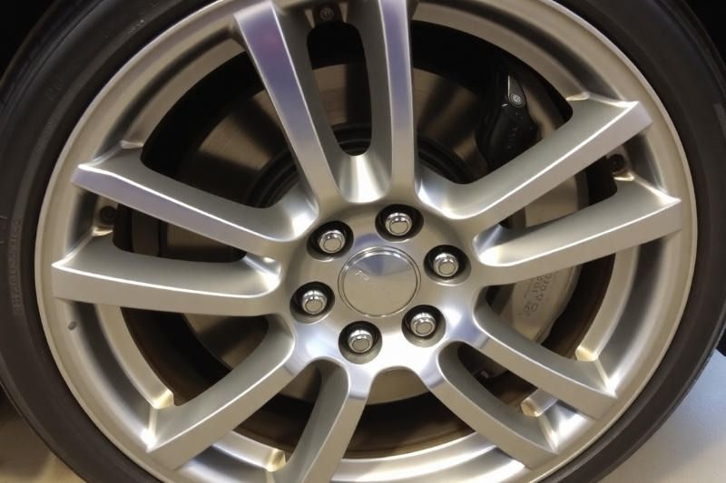 Silver car wheel with a black tire.