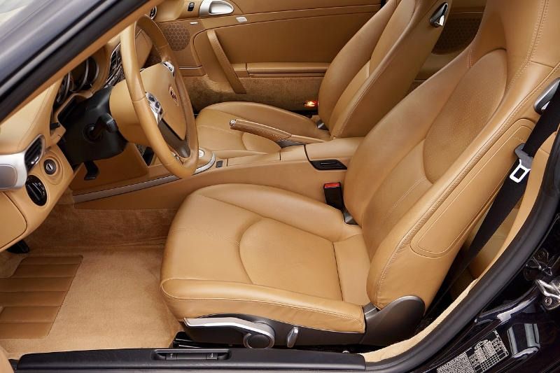Tan leather car interior with seats, dashboard, and floor mats.