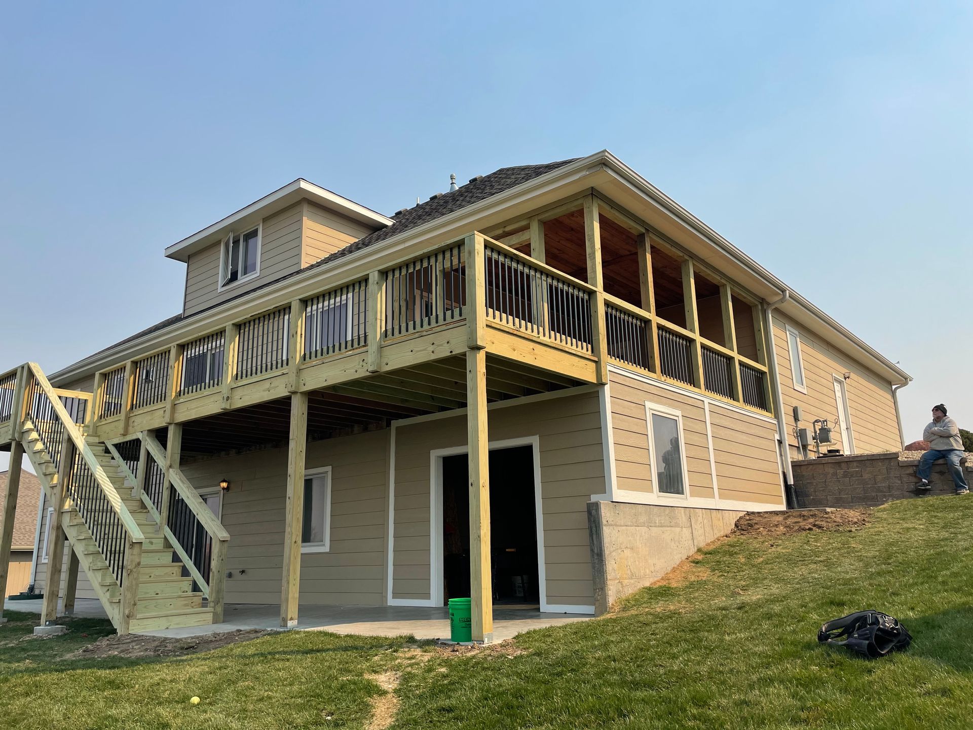 Two-story house with a wooden deck and staircase, tan siding, and a screened-in porch.