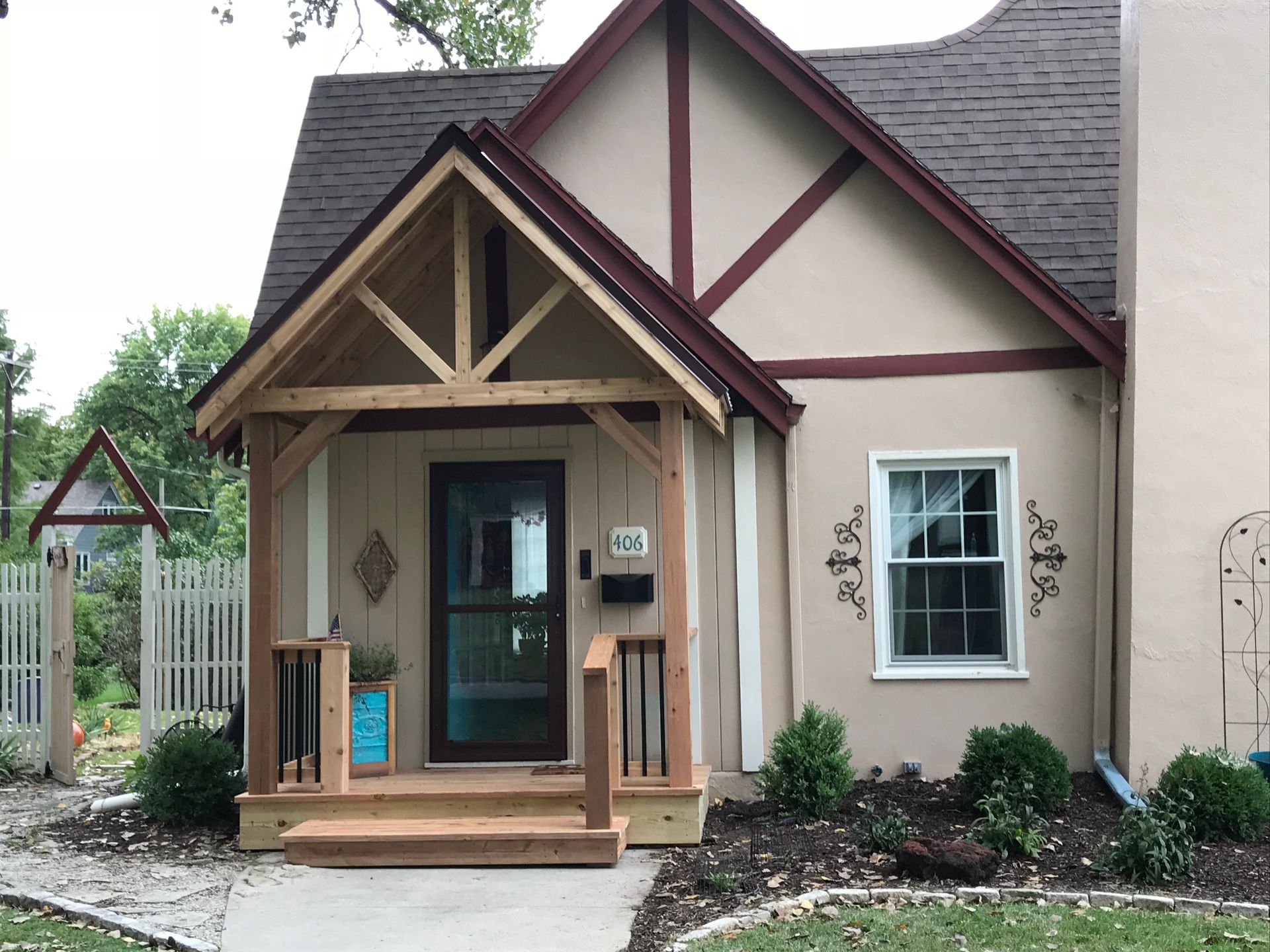 Cottage-style home with a wooden porch, brown roof, and tan stucco exterior.