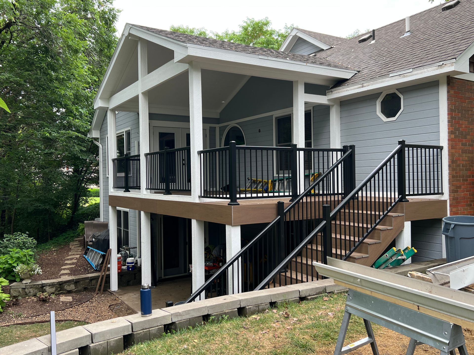 House with a new deck and stairs, black railings, brown and gray siding, and light blue walls.
