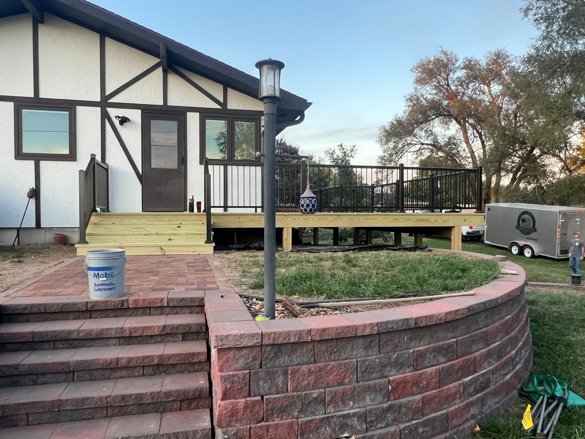 Exterior view of a deck and brick retaining wall next to a house with Tudor-style trim.