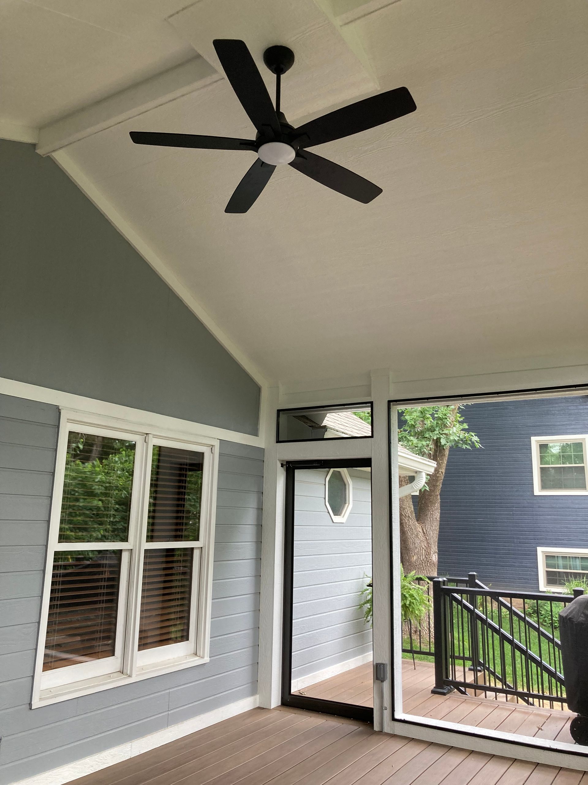 Screened porch with gray walls, white trim, and a black ceiling fan.