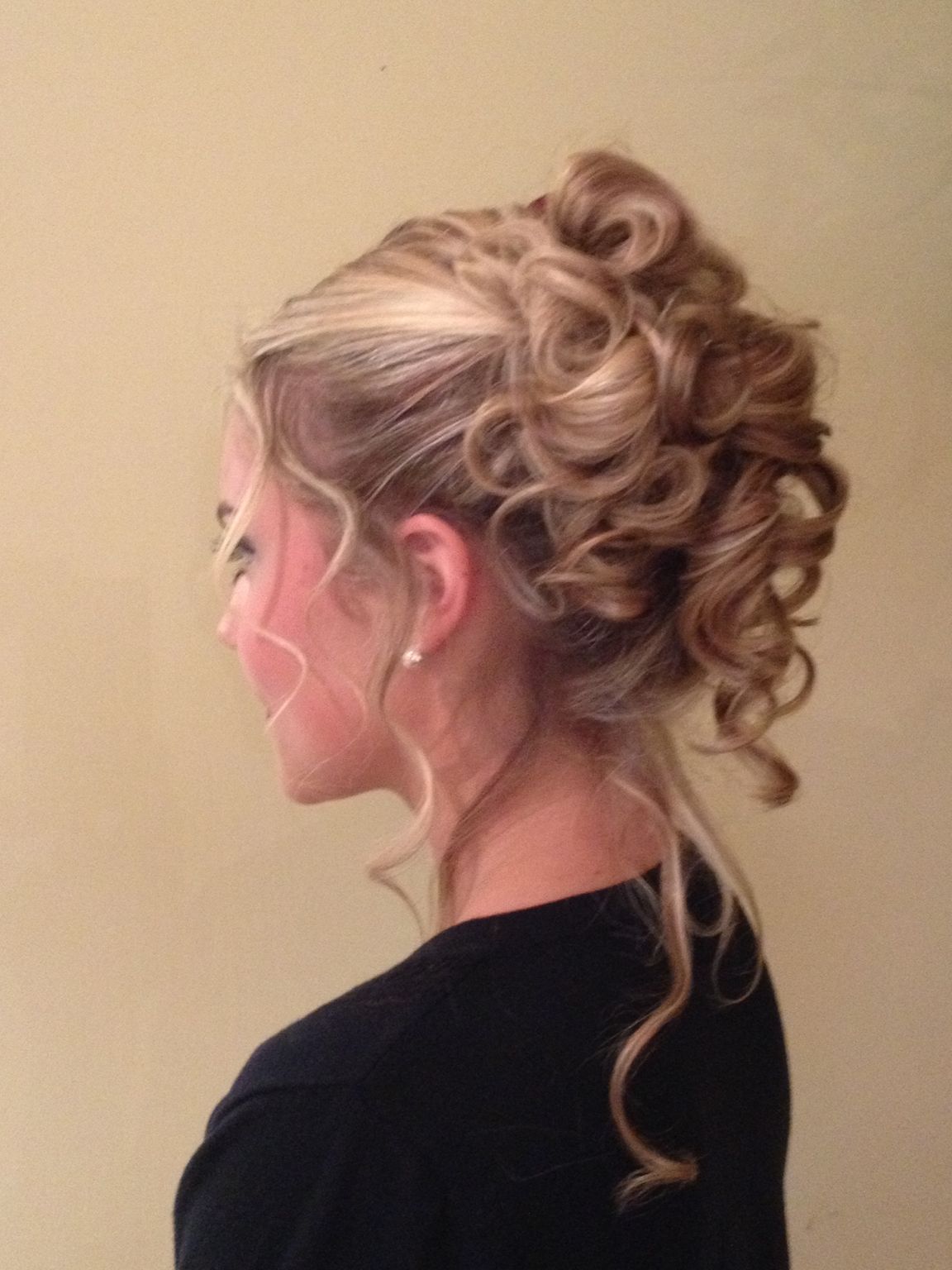 The woman is wearing a black shirt and has her hair in a bun 